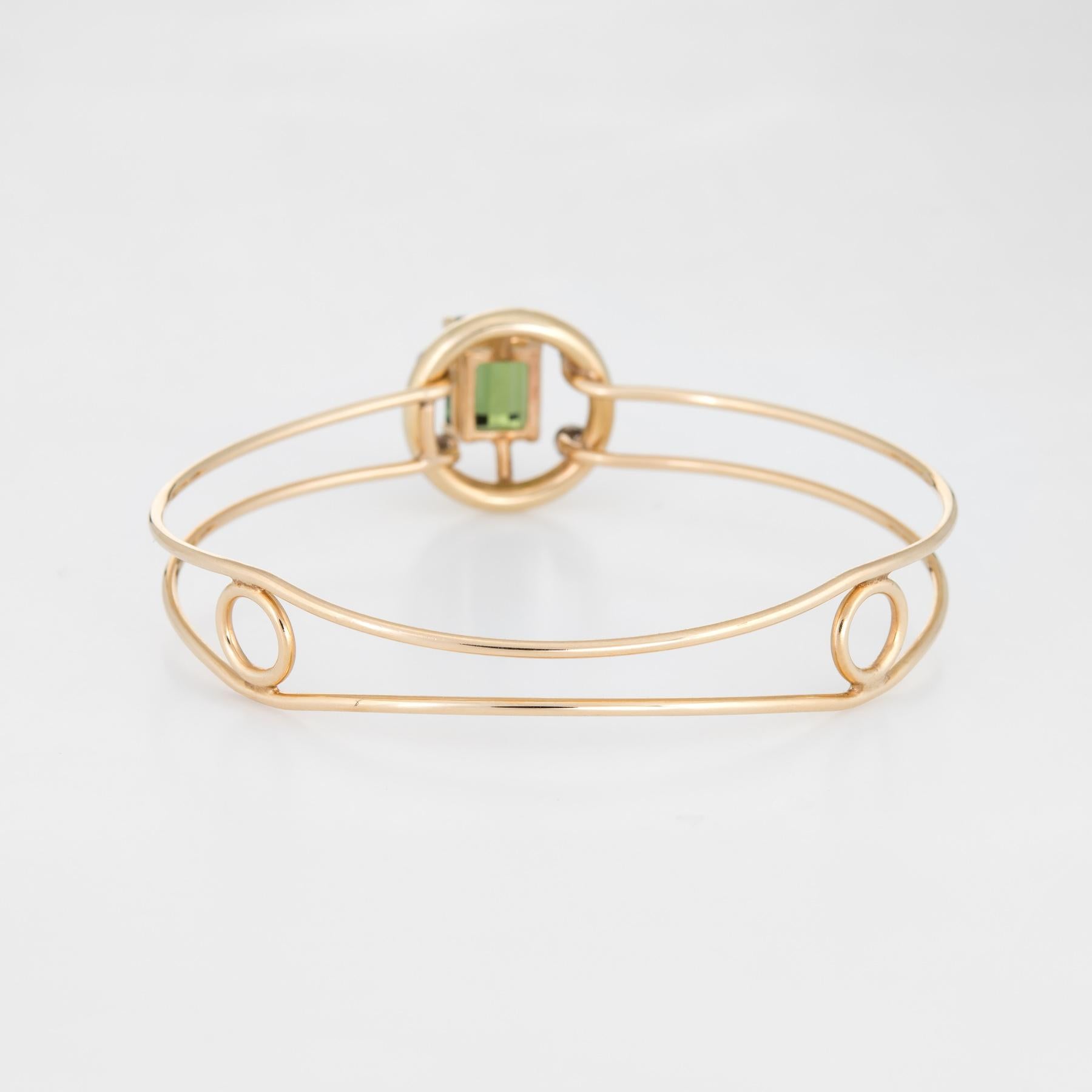 Stylish and finely detailed vintage green tourmaline & diamond bangle bracelet, crafted in 14 karat yellow gold.

Emerald cut green tourmaline measures 10.5mm x 8mm (estimated at 3.70 carats), accented with four round brilliant cut diamonds