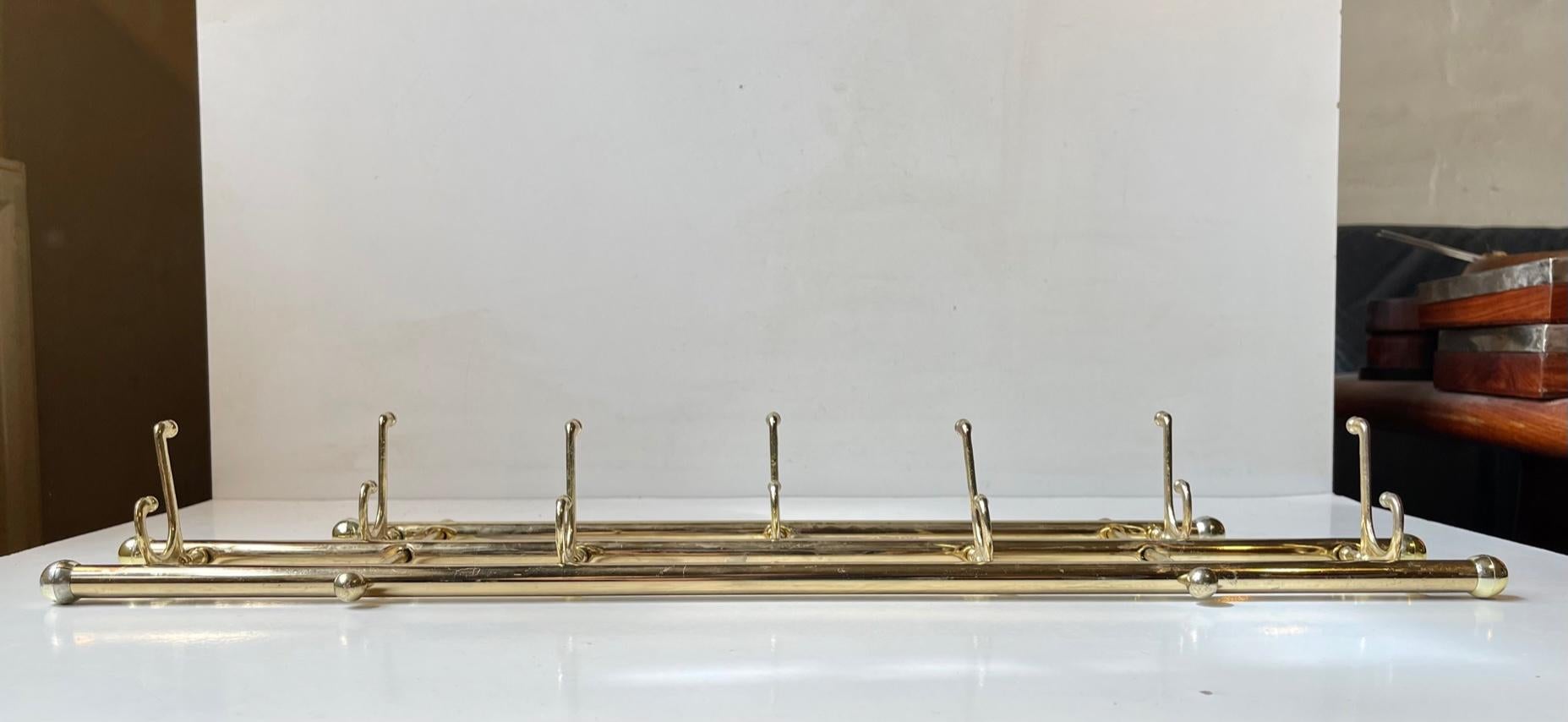 Decorative towel, kitchen or small coat rack with 5 articulating/foldable double hooks. It made from gold chromed metal, brass and plastic. Unknown maker circa 1970-80. Measurements: w/l: 55 cm, h: 18 cm, Dept: 2 cm