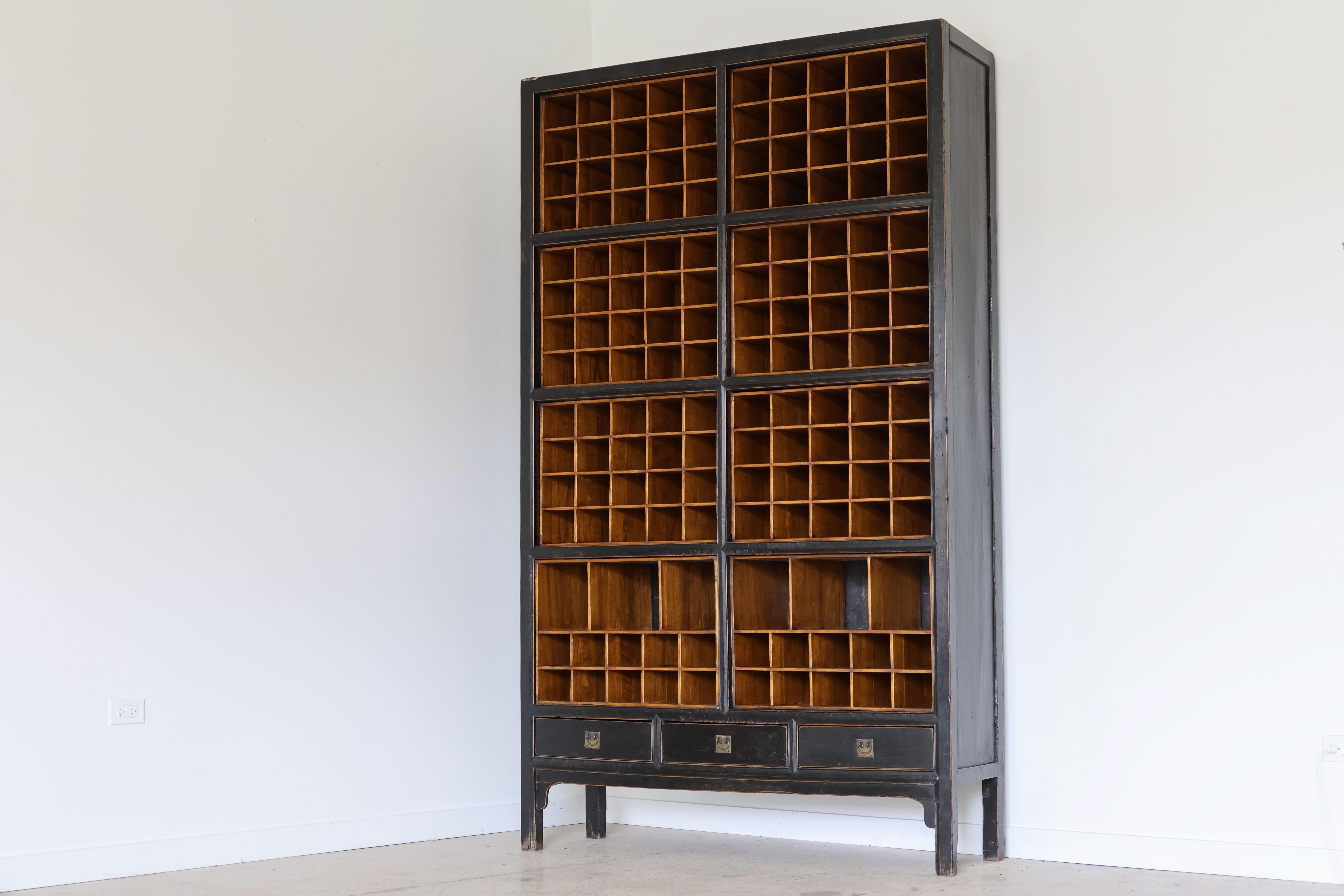 Extra tall vintage black lacquered organizer salvaged from a Chicago downtown architects office.
Likely used as a mail sorter, this mammoth piece fits wine bottles!
Lowest two cubby frames have the option to slide out completely.
Three drawers along