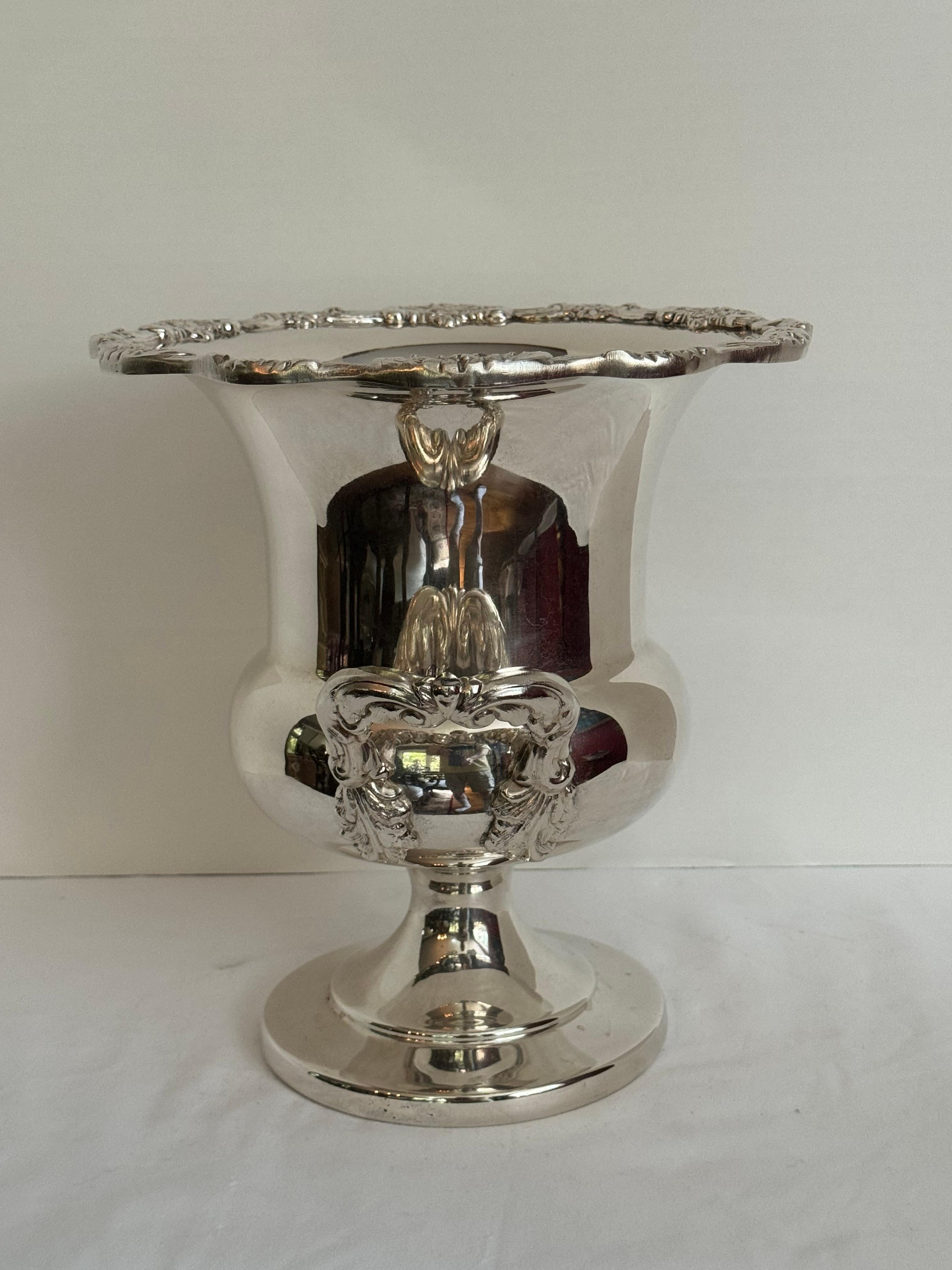 Large vintage silver plate wine cooler by Towle Silver Smith Mfg Co .

silver plate wine or Champagne Cooler.
This trophy-style wine chiller has two decorative handles and the top edge has a nice floral patterns .
Could be used as a champagne/wine