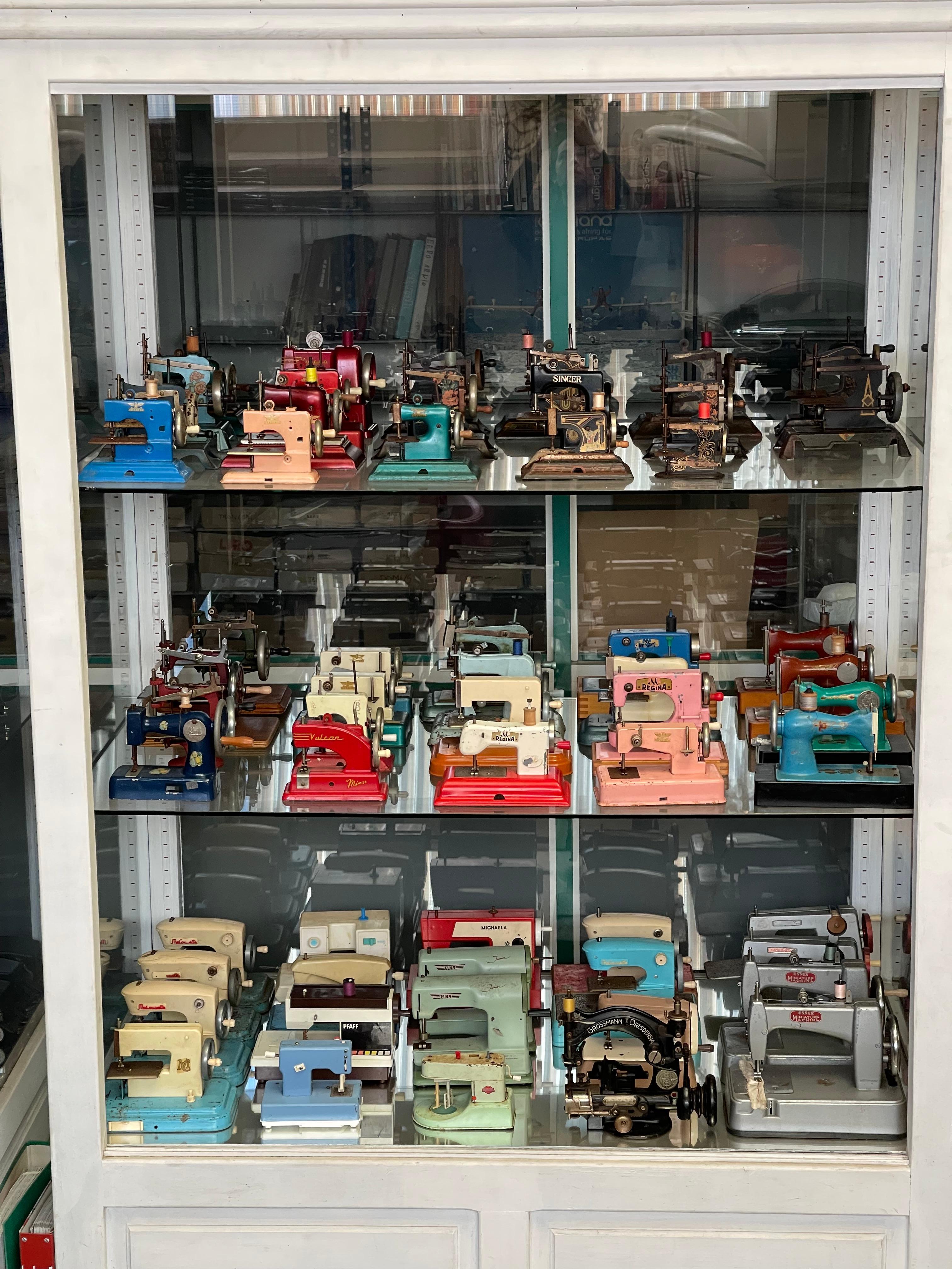 This fascinating collection of vintage hand-crank sewing machines, originally designed as toys for children, showcases a wide range of models produced throughout the 20th century. These miniaturized machines were often gifted to young girls,