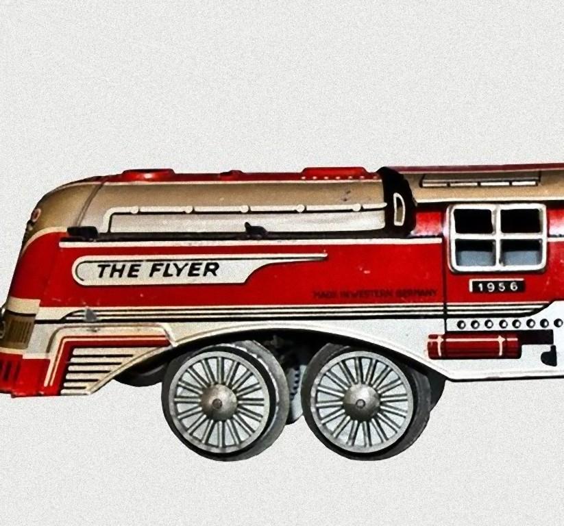 Die Flyer-Lokomotive mit Wagen von 1956 ist ein seltenes altes Spielzeug.

Vintage wind up tin toy train made of two pieces, locomotive and coach.
Der ursprüngliche Satz bestand aus drei Teilen, von denen einer fehlt. 
Hergestellt 1956 in