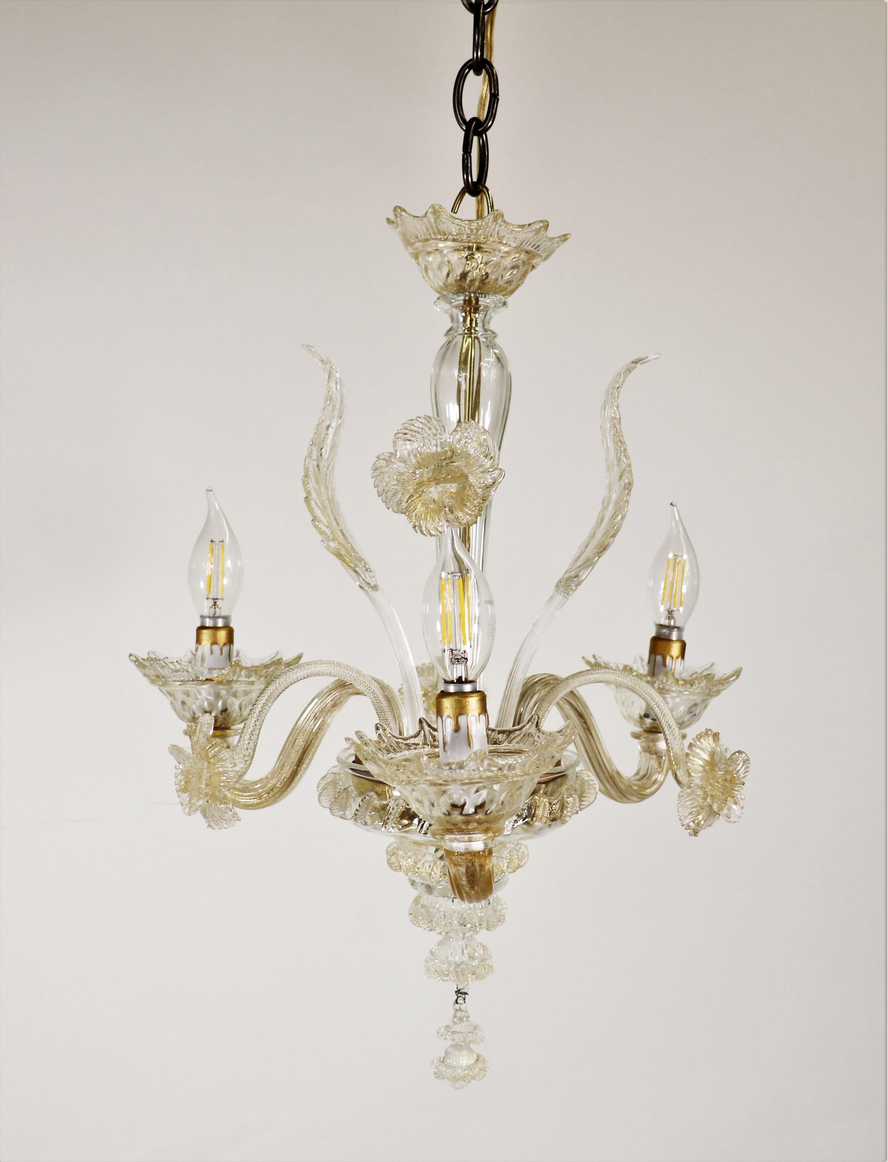Despite its small size, this classic floral Murano three-arm chandelier creates quite a statement. Stylized with sprouting daffodils and leaves, the undulating arms hold bobeches with petal-shaped rims. The hints of gold dust dispersed throughout
