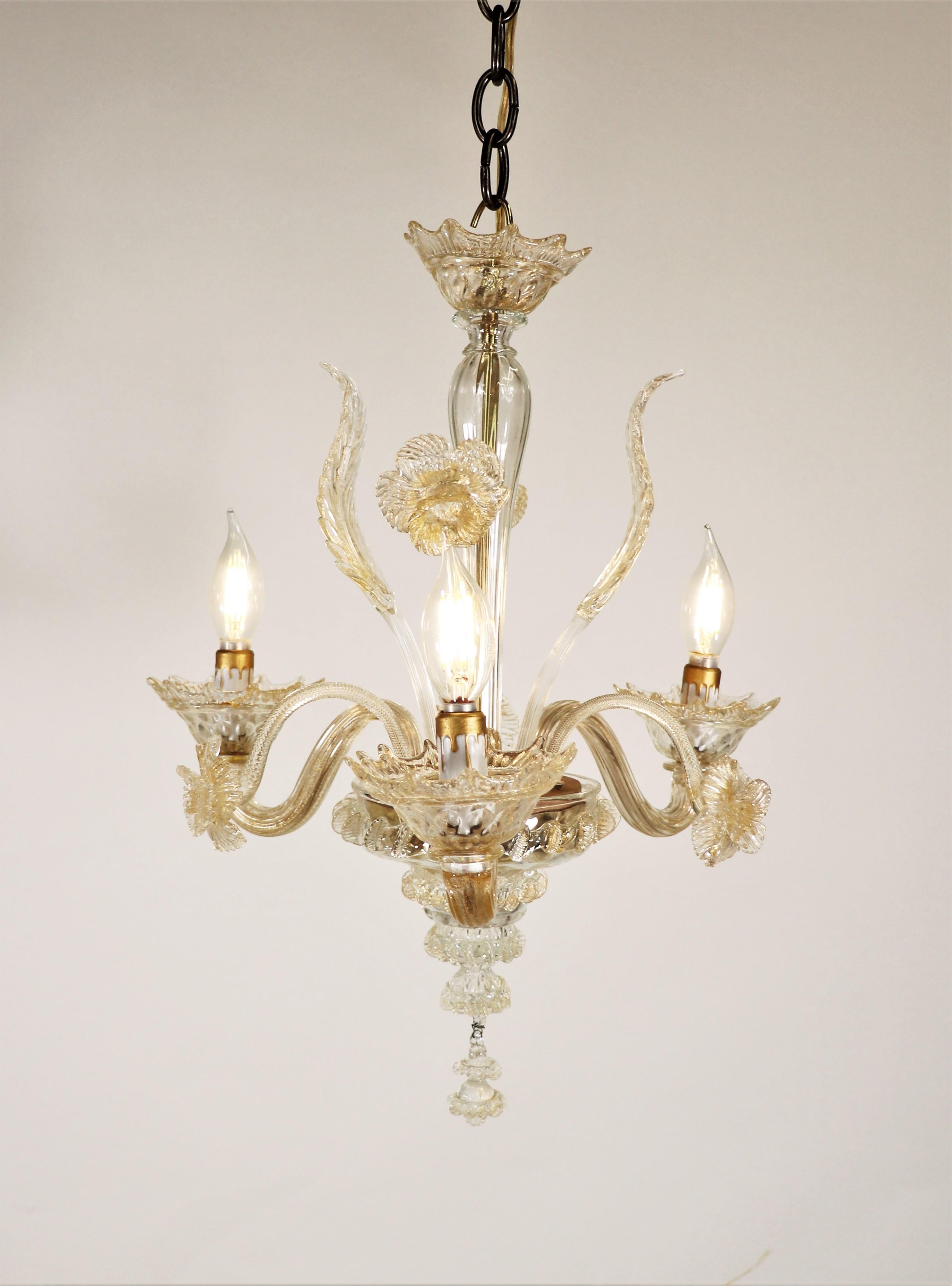 Despite its small size, this classic floral Murano three-arm chandelier creates quite a statement. Stylized with sprouting daffodils and leaves, the undulating arms hold bobeches with petal-shaped rims. The hints of gold dust dispersed throughout