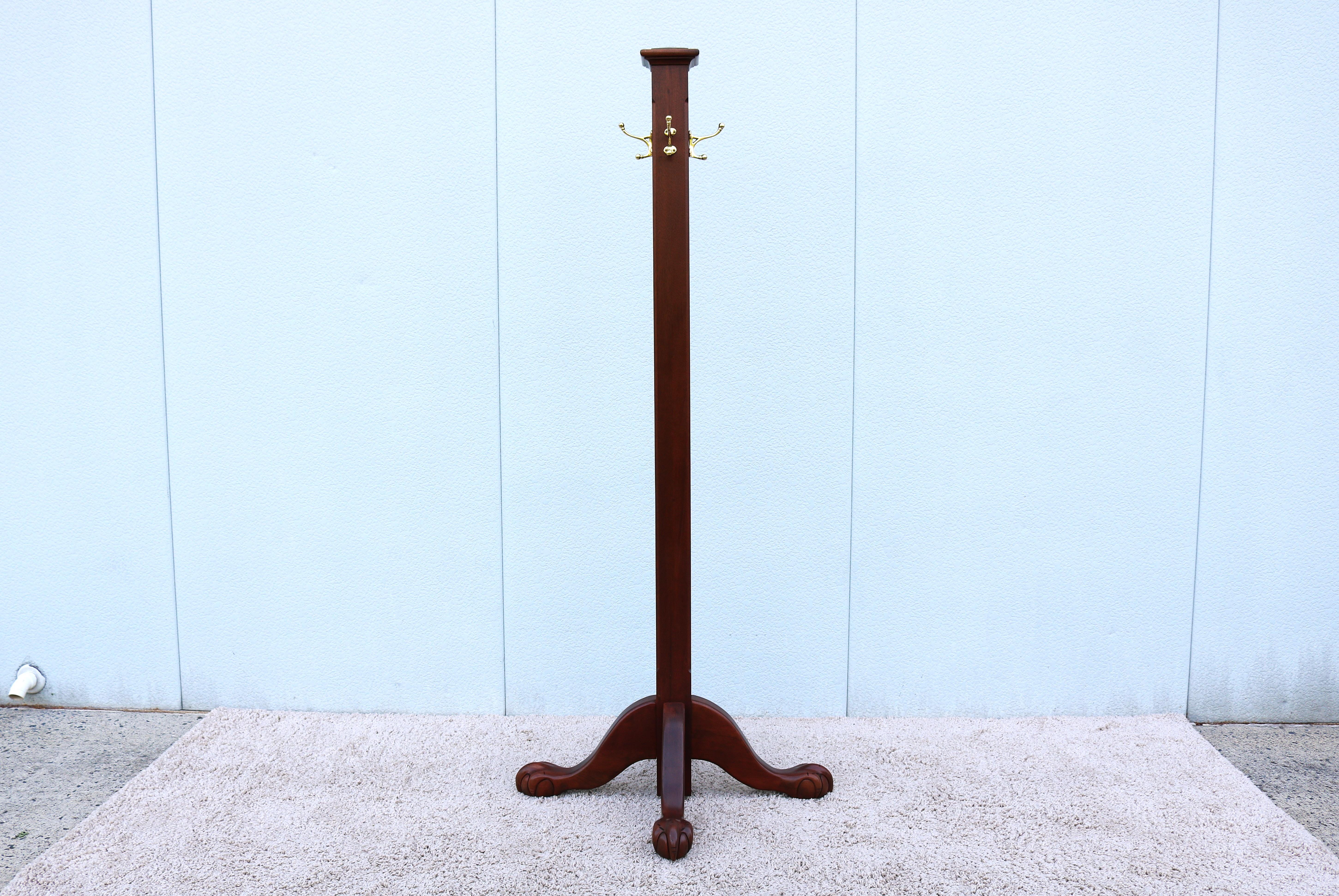 Fabulous traditional freestanding coat rack in solid mahogany wood and solid brass hooks. Also commonly referred to as a hat stand, hall tree, or coat stand.
It's influenced by Arts and Crafts, or Colonial Revival design elements. 
A classic