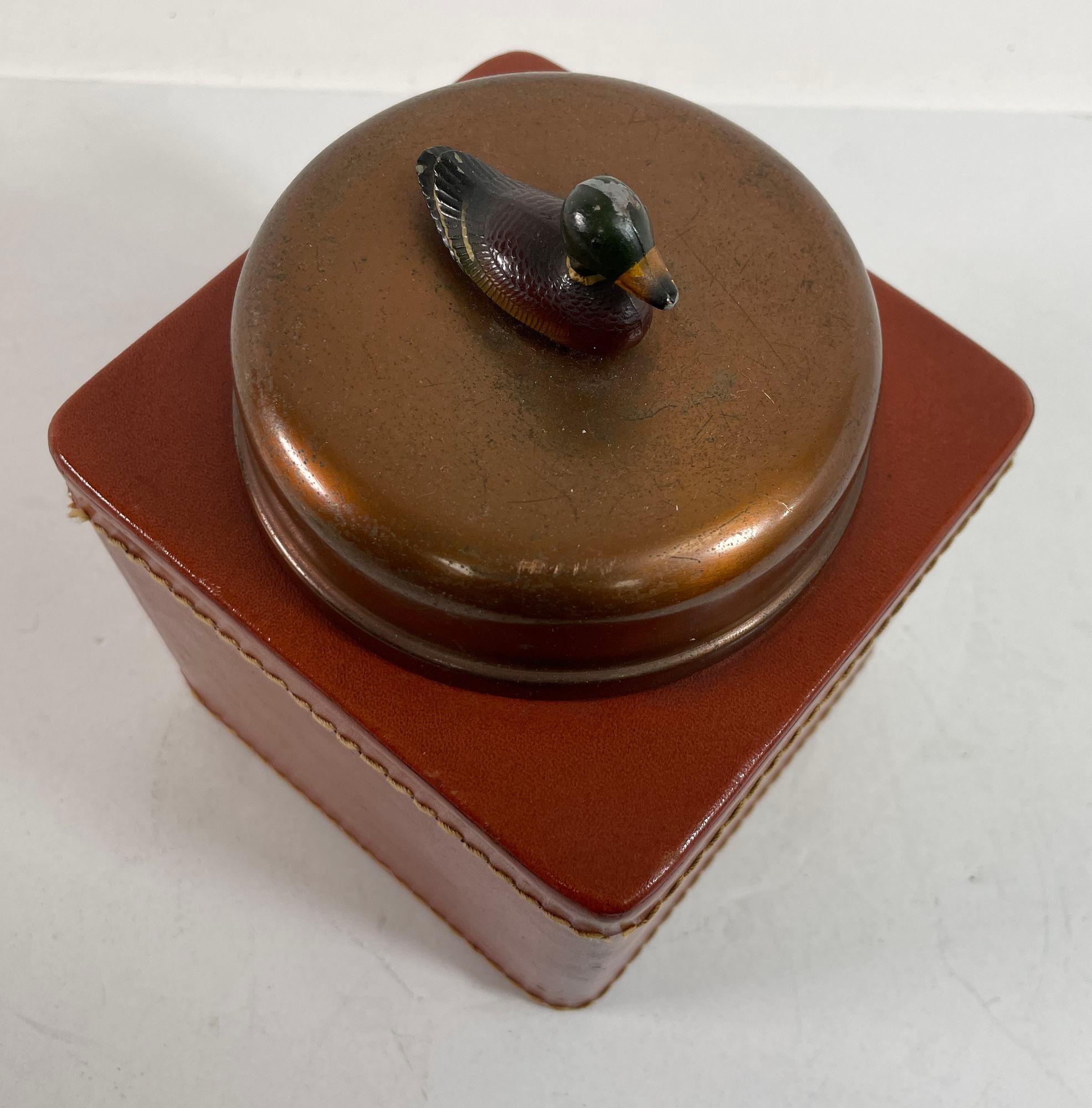Vintage Traditional Mallard Duck Motif Leather Tobacco Humidor Jar.
Vintage Tabak Humidor quadratische Box in Cognac Farbe Leder eingewickelt.
CIRCA 1950, aus kupferfarbenem Metall, mit einer Lederhülle und einem Metalldeckel, der mit einer Skulptur