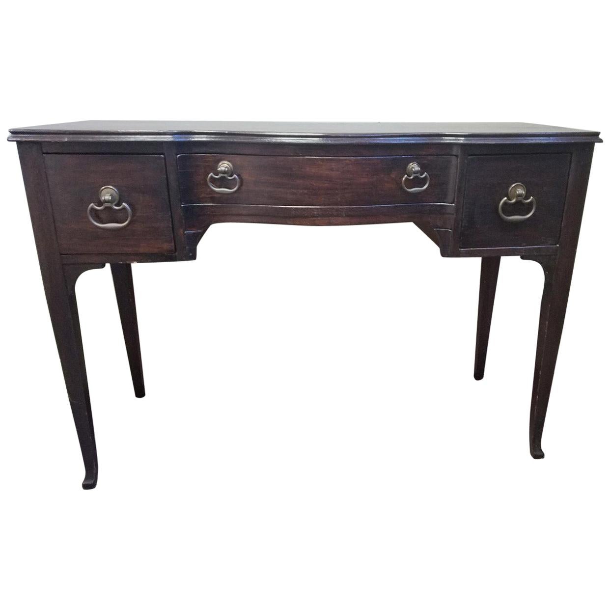 Vintage dark walnut stained wood writing desk or vanity. The three front drawers offer lots of storage and are lined with the felt. The antique solid brass pulls are original. The back is also stained the same color. The drawers are dove tail