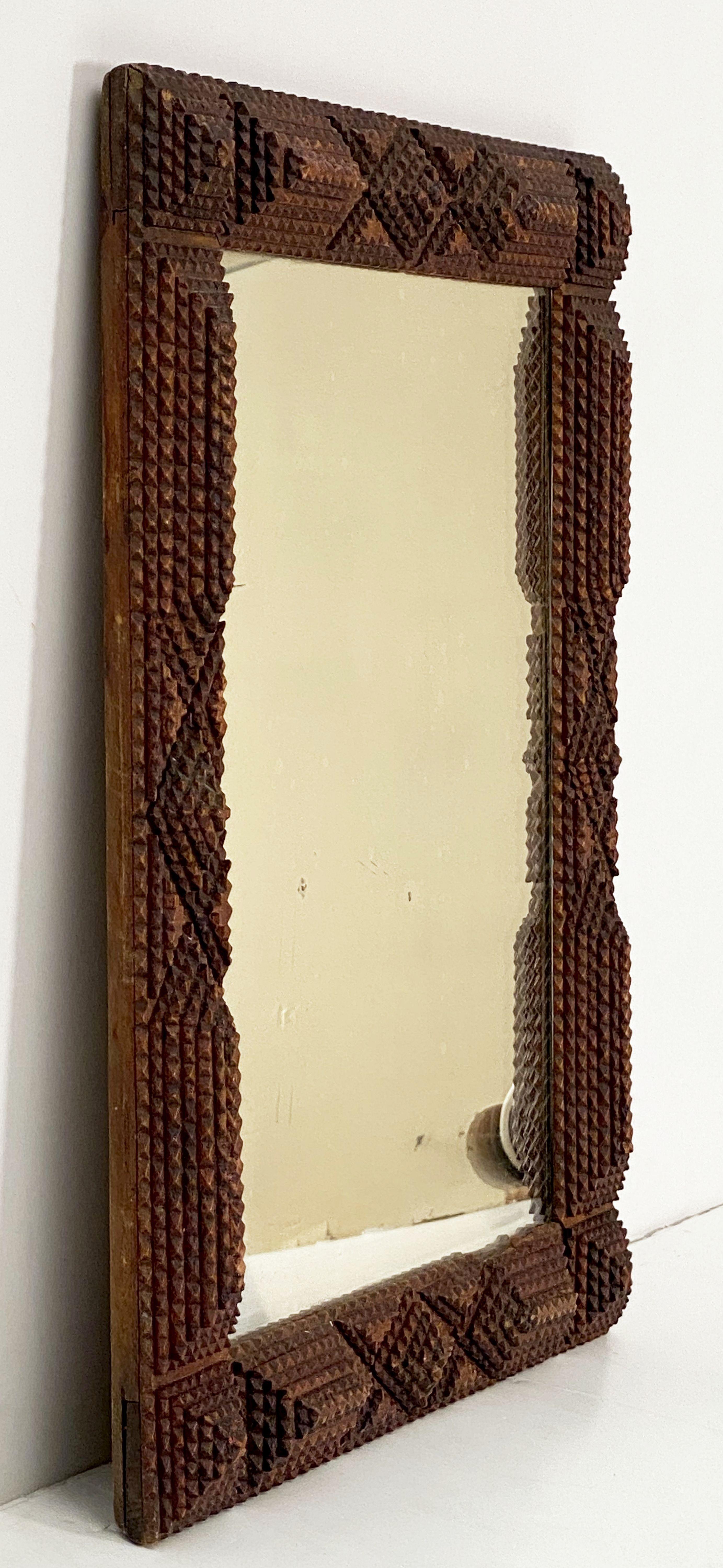 A vintage English Tramp Art mirror featuring a rectangular frame with an ornamental relief design. 

Dimensions are 20 1/4 inches x 16 1/2 inches.

Tramp Art was an art movement found throughout the world where small pieces of wood, primarily