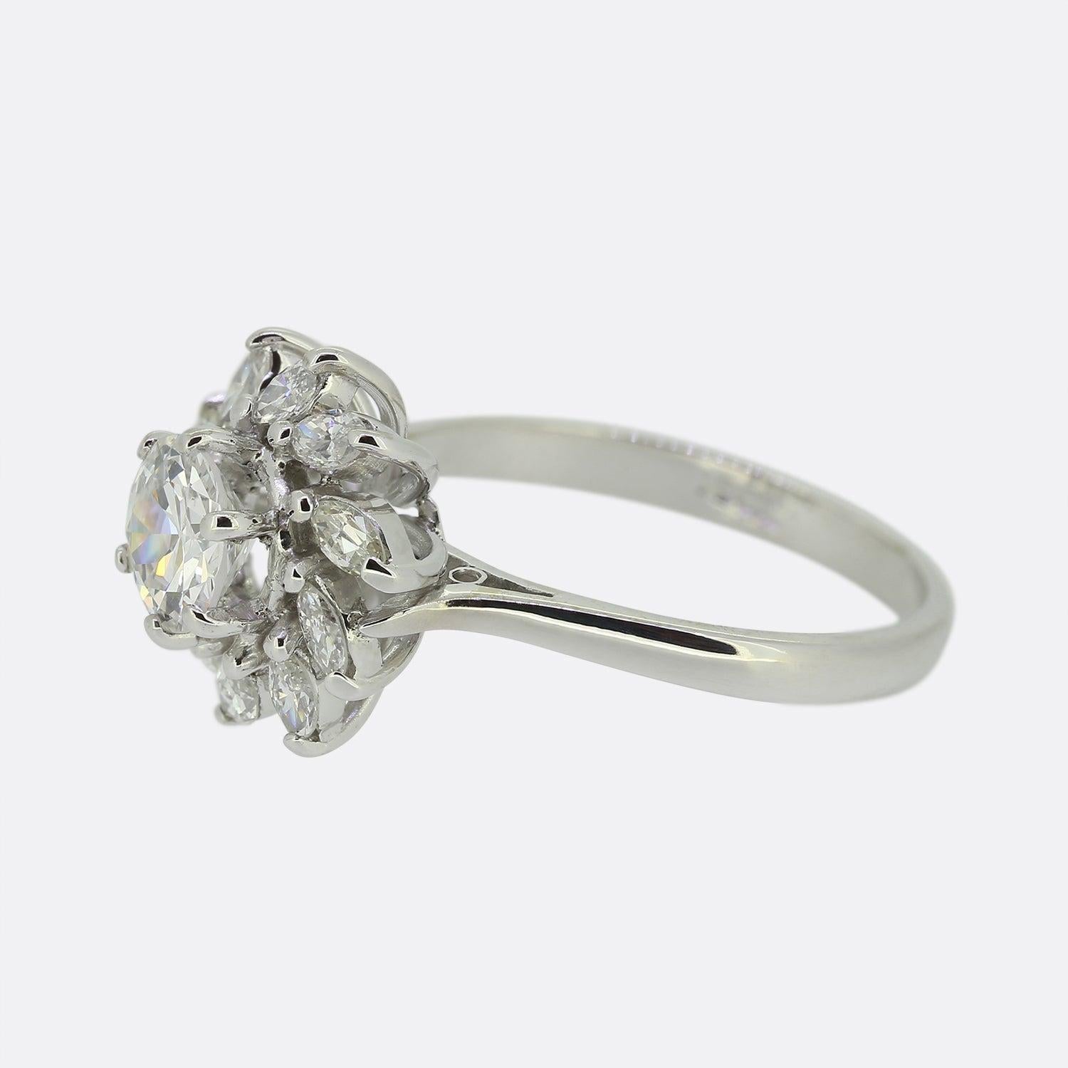 This is a lovely diamond cluster ring that dates back to the mid 20th century. The focal point of the ring is a 0.75 carat transitional cut diamond that is surrounded by a cluster of marquise cut diamonds. It is crafted in 18ct white gold and the