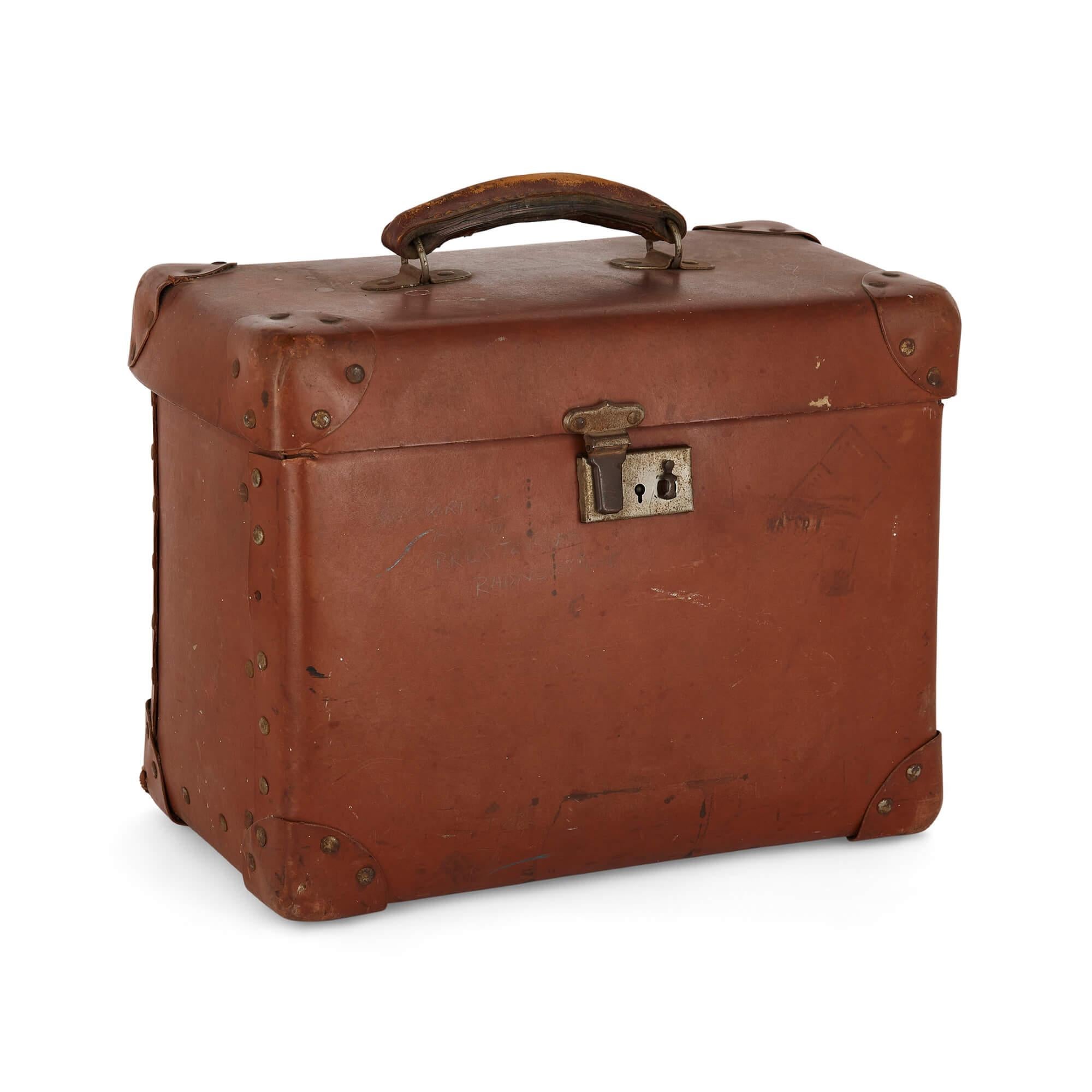 Vintage travel case and top hat by Tress & Co., London.
English, 20th century.
Measures: hat: height 16 cm, width 26 cm, depth 31 cm.
case: height 27 cm, width 35 cm, depth 20 cm.

These intriguing objects, a vintage leather travel case and a