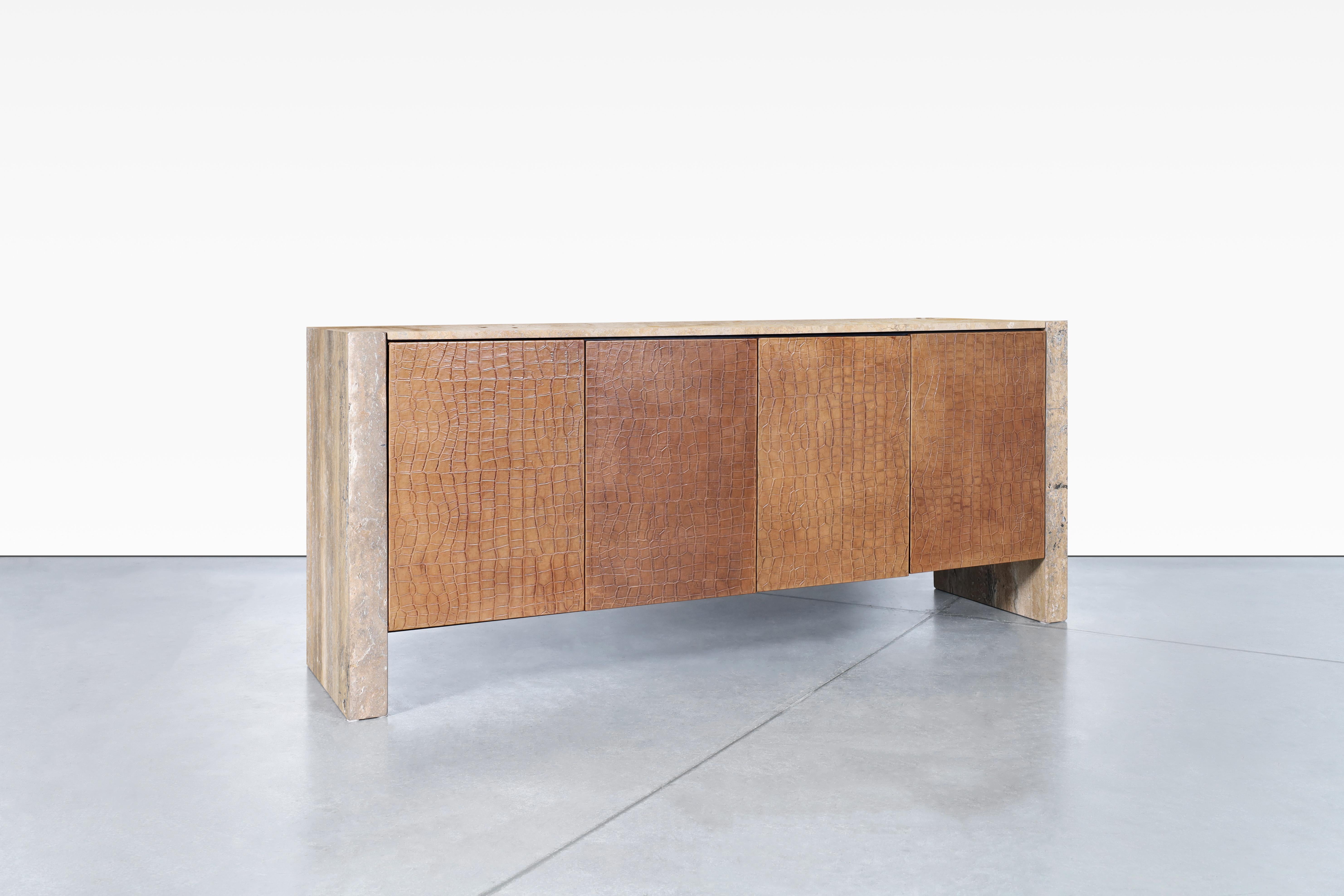 This beautiful vintage credenza is a true statement piece for any room. The luxurious crocodile-textured leather on the doors exudes elegance and refinement. The travertine sides and top provide a sturdy and durable base while also lending a touch