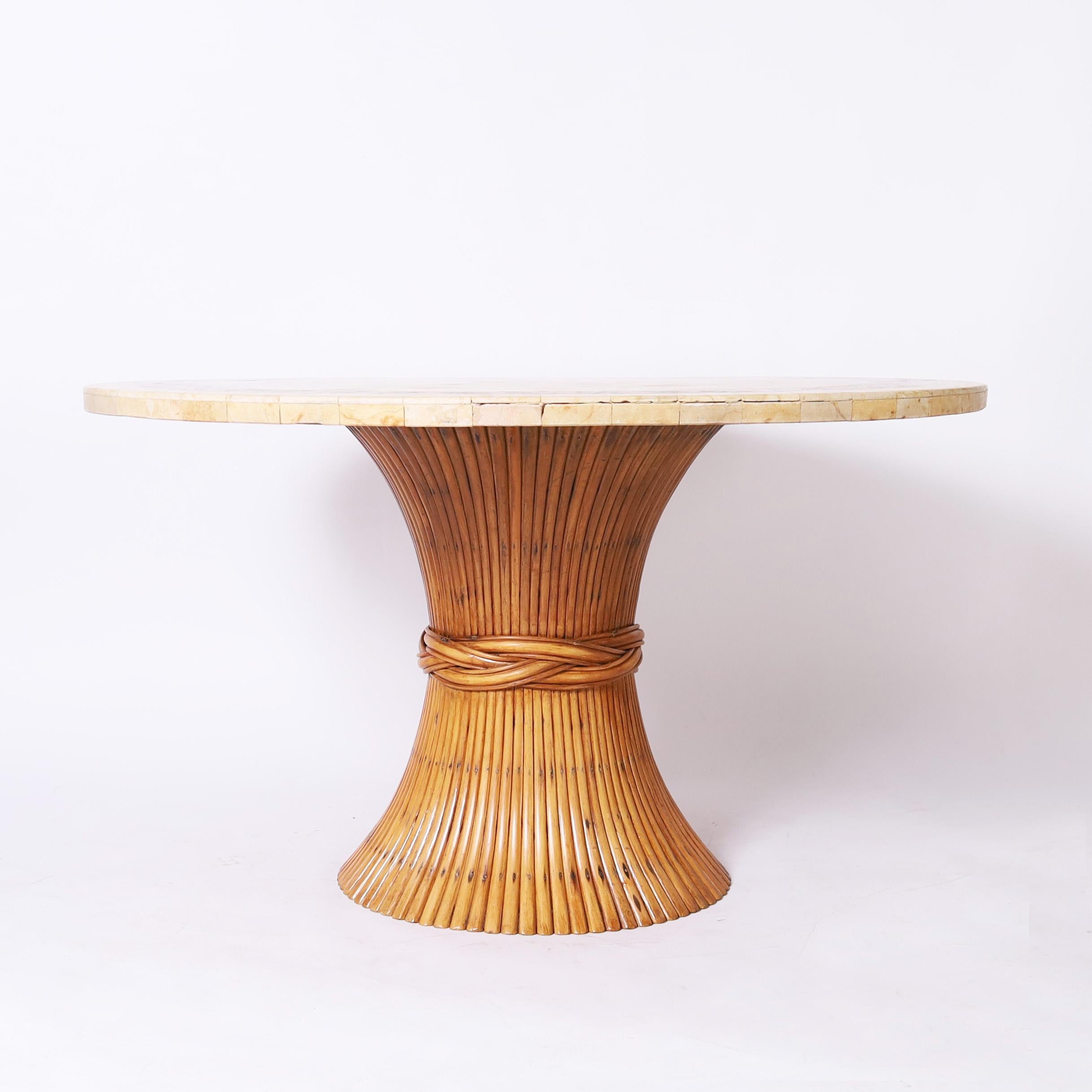 Impressionnante table de dînette du milieu du siècle à l'élégance décontractée, avec un plateau rond orné d'une mosaïque de travertin et d'une bordure géométrique en pierre, sur une base en rotin italien stylisé en forme de gerbe de blé.