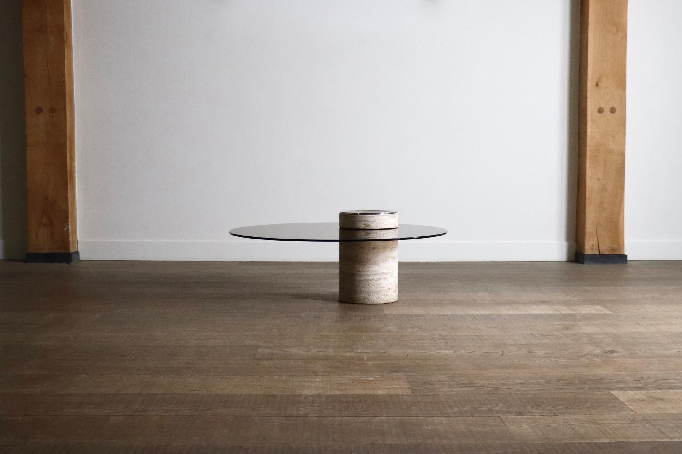 Unglaublicher Couchtisch aus Travertin, mit einer Tischplatte aus Rauchglas und einem Aschenbecher aus Metall, hergestellt in Frankreich in den 1970er Jahren.

Ein auffälliges Design, das durch die Einklemmung des Glases zwischen den zylindrischen