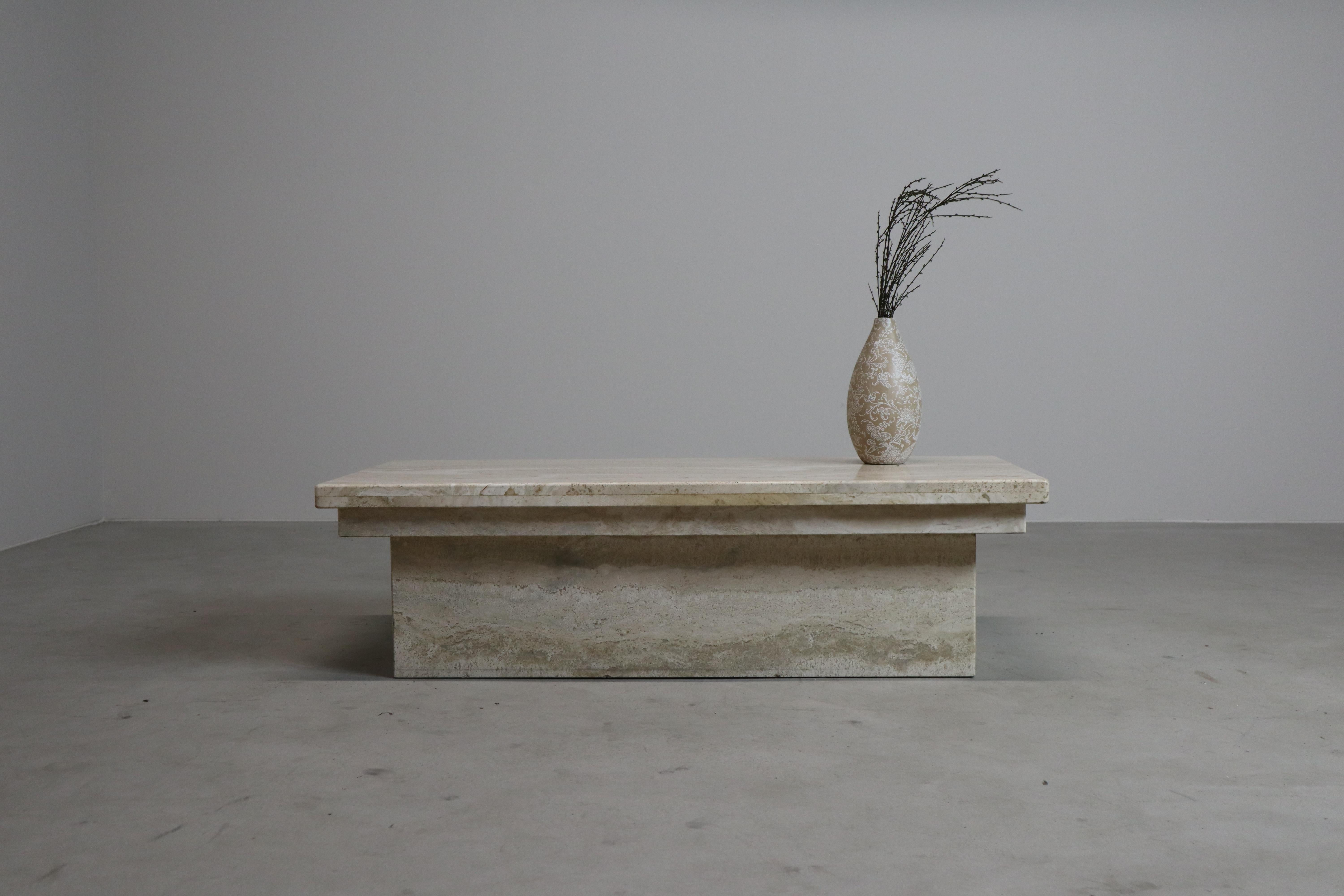 Striking vintage travertine coffee table, made in Italy during the 1970s. The rectangular tabletop with bold overhang rests on a clean-lined base, fully constructed from travertine slabs. The soft beige and ivory veining gives the stone a natural