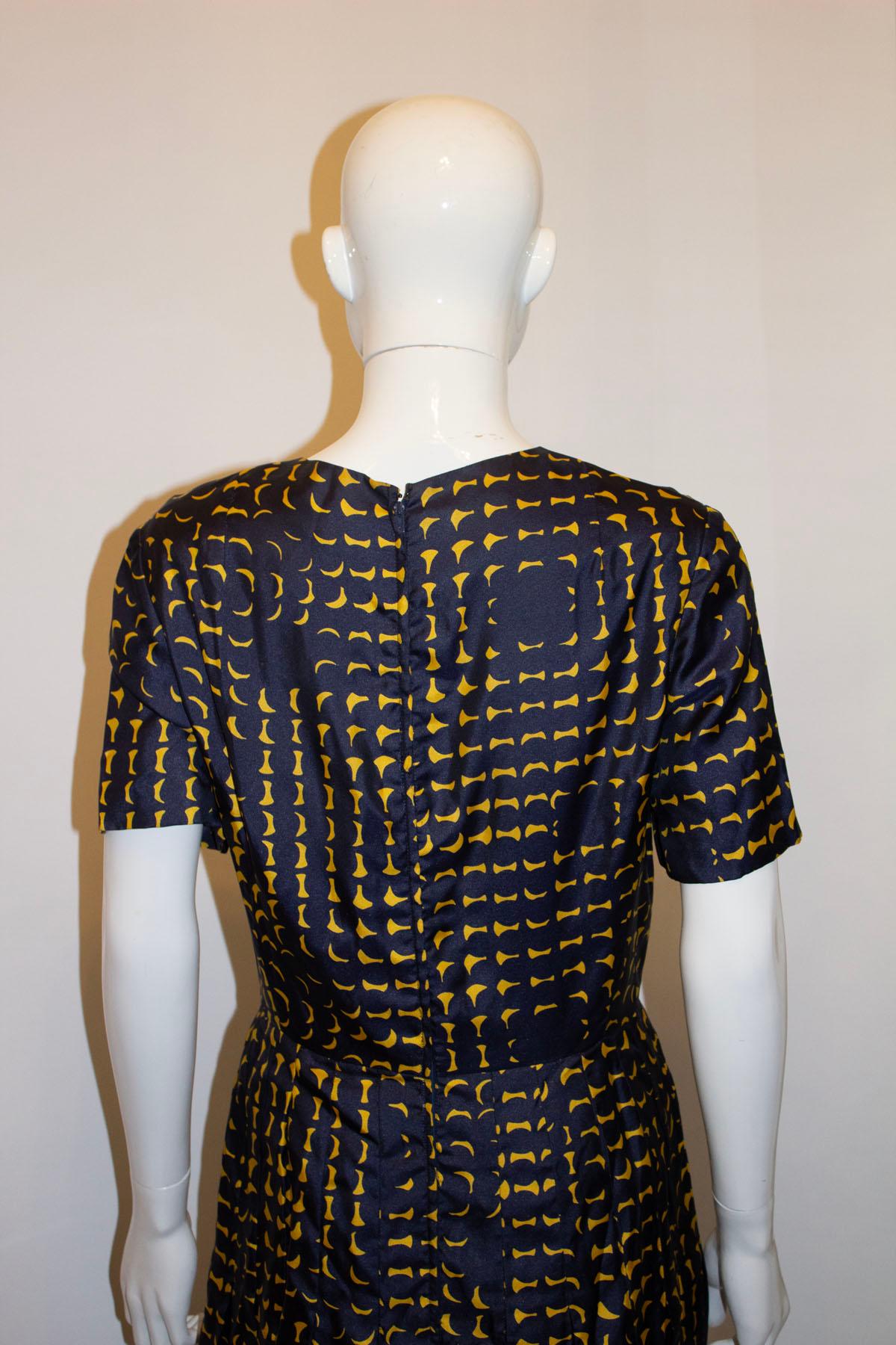 A vintage silk day dress by Treacy Lowe. The dress is in a super soft silk , in a blue and yellow print. It has a round neckline, short sleaves and central back zip. It has sewn in pleats and thus produces and very sleek line, no bulking over the