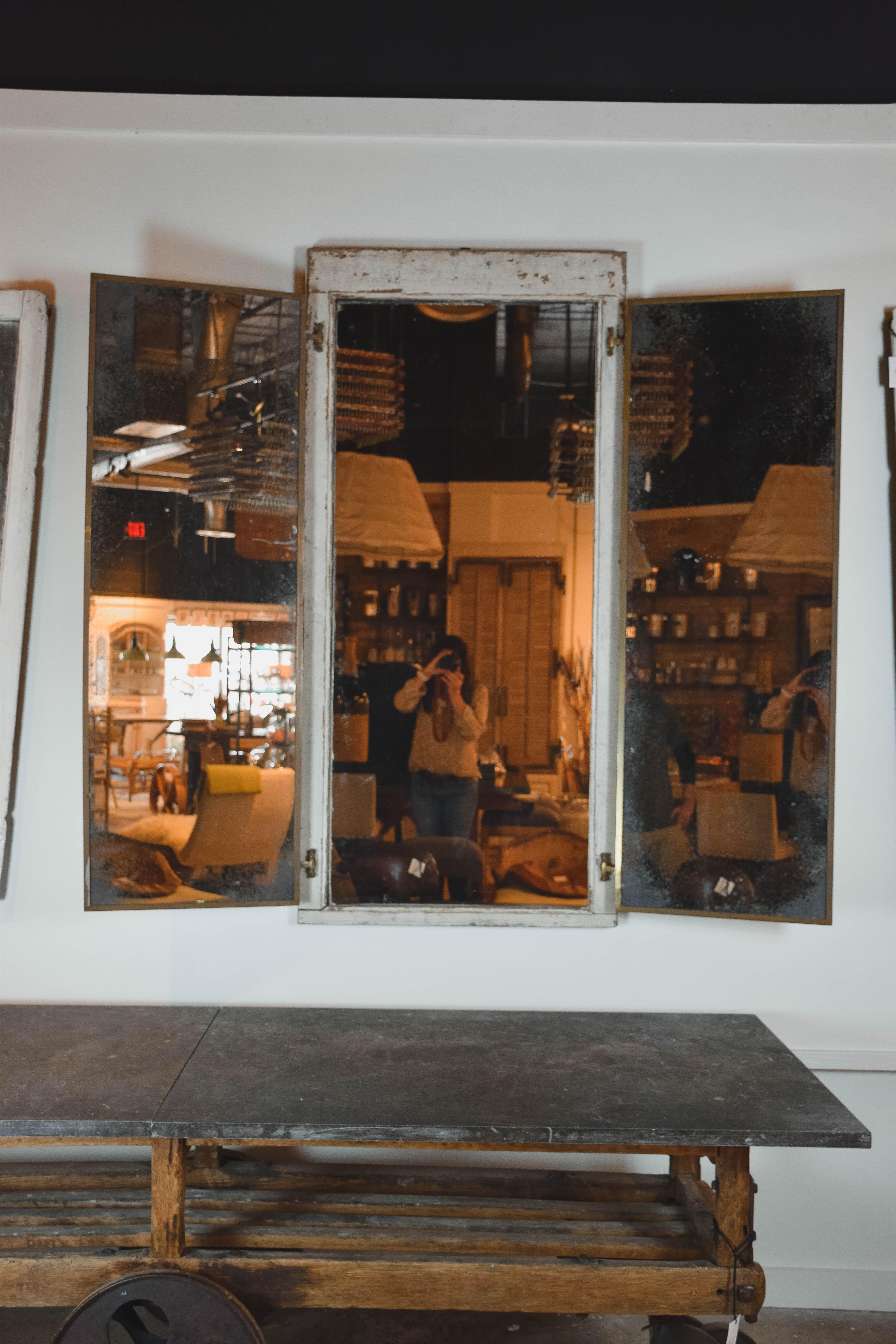 We found this wonderful vintage tri fold full length mirror in Provence. The mirror has a great aged painted patina with some wood showing through in worn areas. The three mirrors are joined with brass hinges and the two side mirrors are surrounded