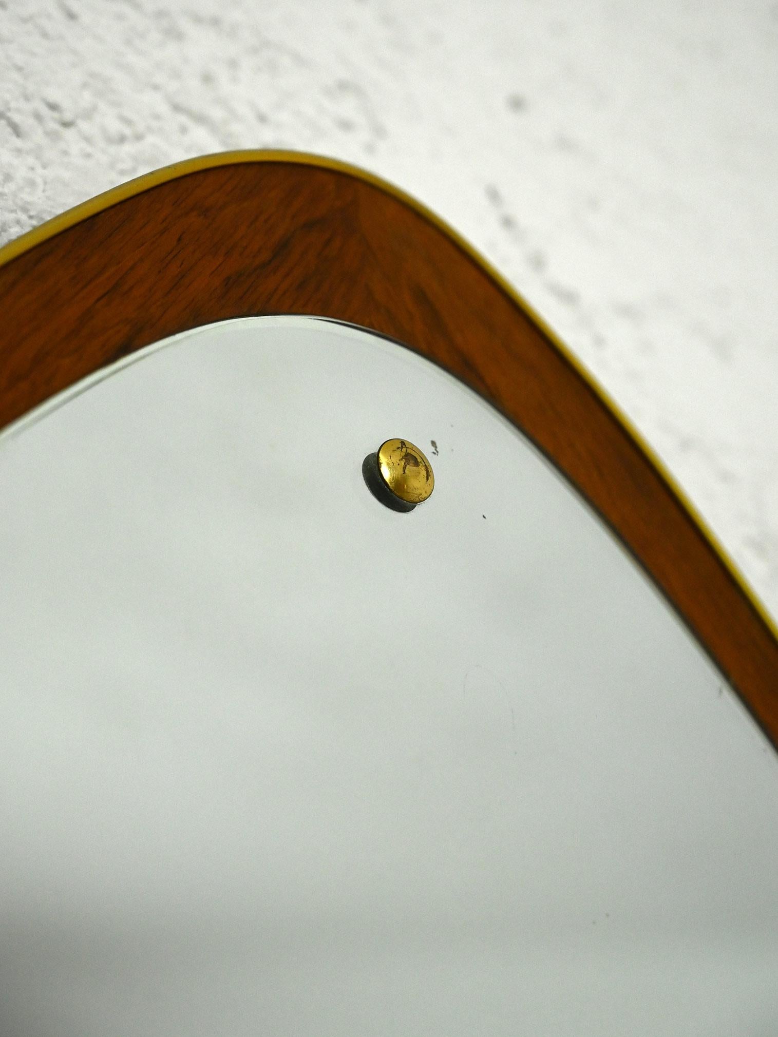 Vintage mirror of triangular shape with slightly rounded corners manufactured in Sweden in the 1950s.

The thin teak wood frame and the use of screw covers highlight its authenticity and unique character. 
Despite its small size, it adds a