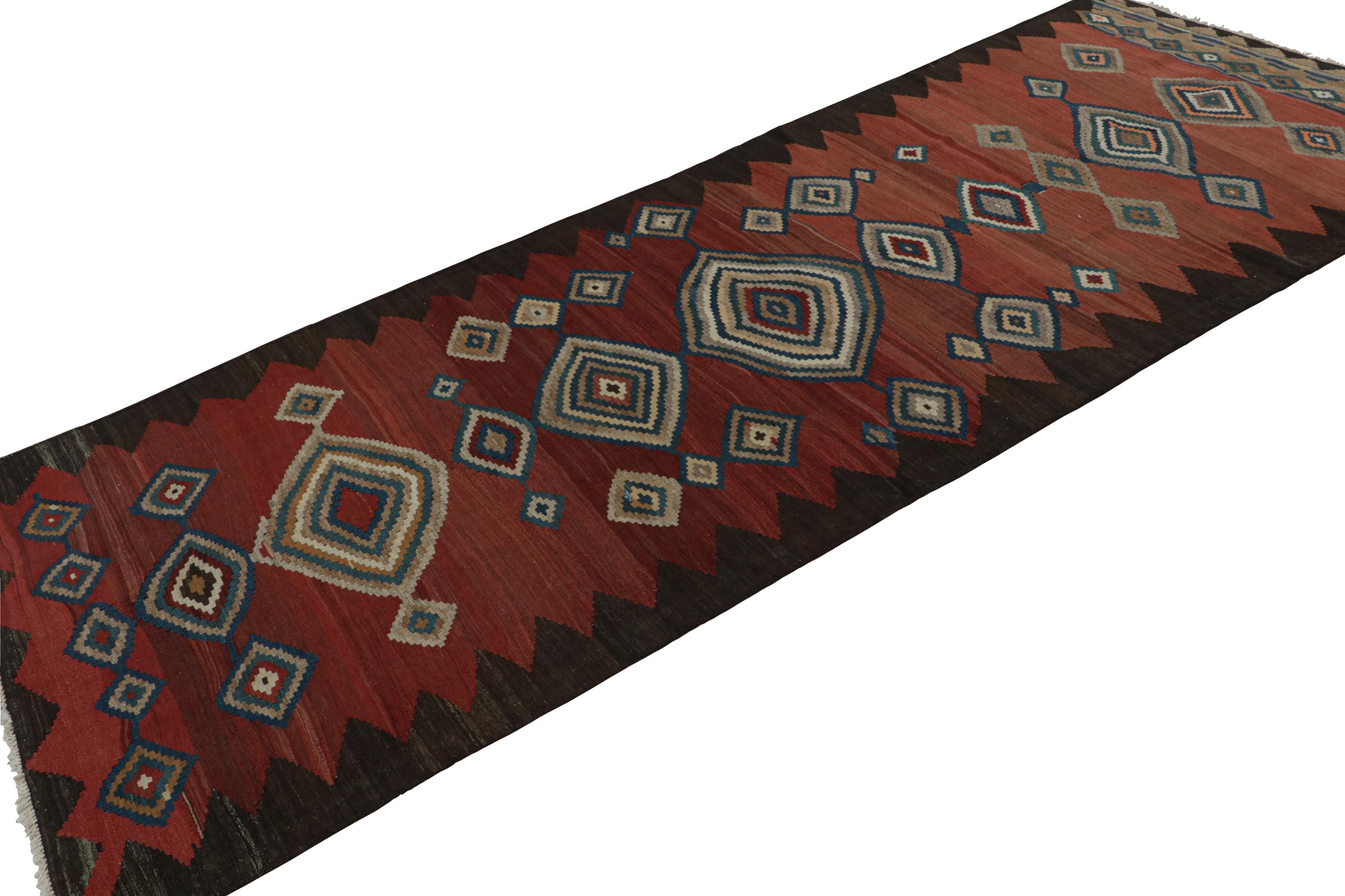 Handwoven in wool, circa 1950-1960, this 5x12 vintage tribal Afghan kilim runner rug features vibrant medallions and geometric patterns in red, blue, beige/brown and black. 

On the design: 

A special piece in the Rug & Kilim collection, this