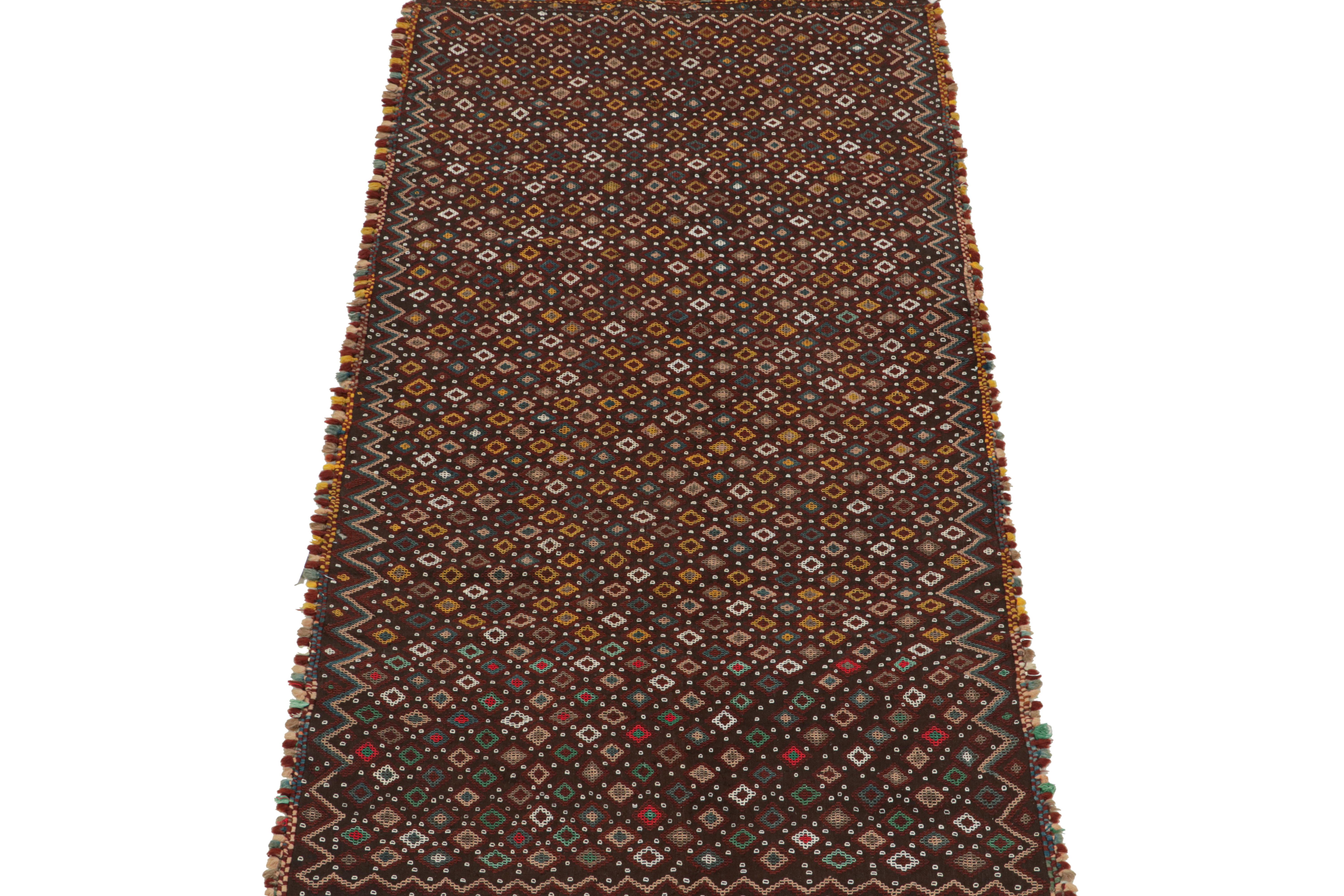 This vintage 4x7 Turkish Kilim is handwoven in wool, and originates circa 1950-1960.

Its colorway is polychromatic, though it favors a chocolate brown field and burgundy in its many colorful geometric patterns. Keen eyes will admire pronounced