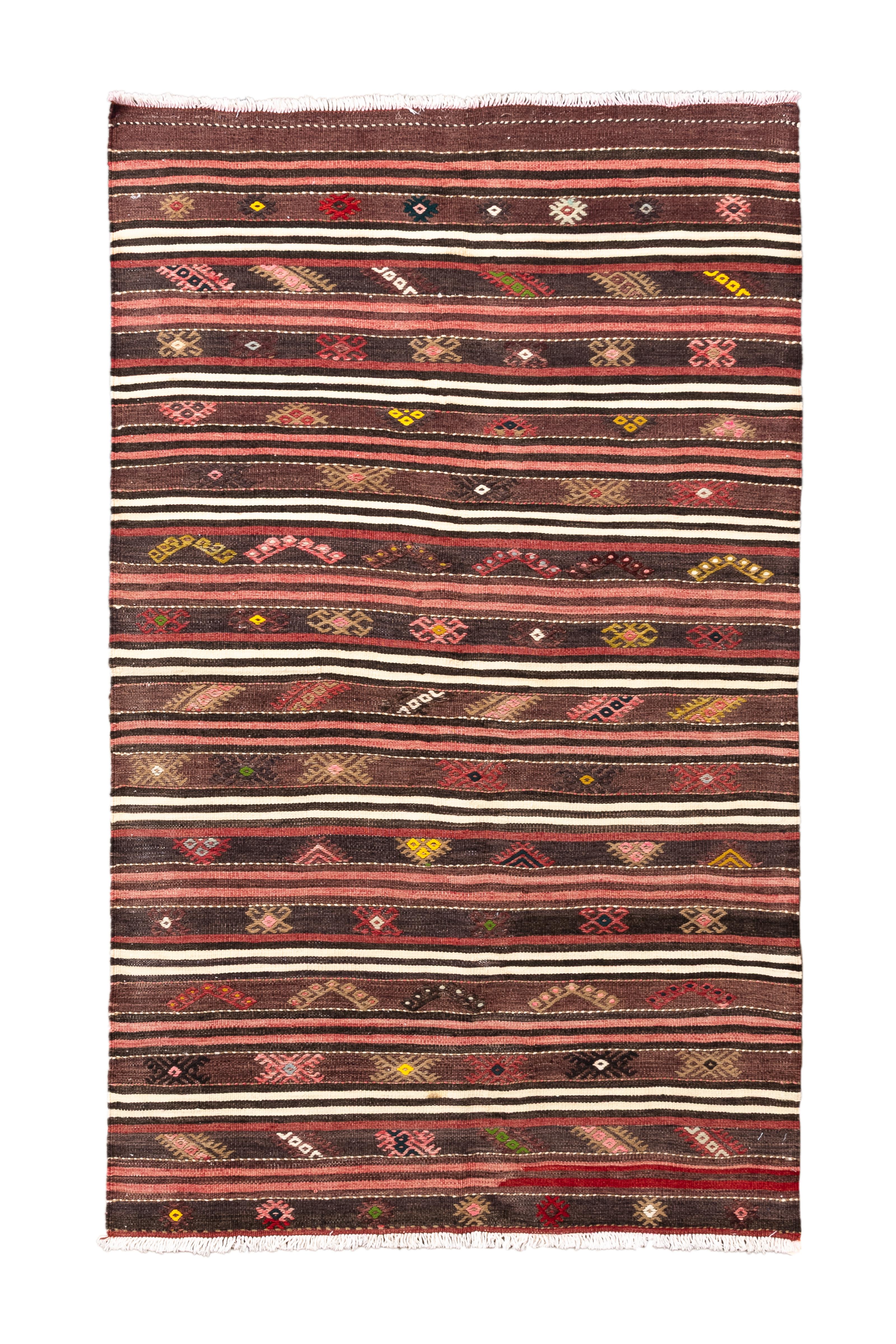 Ein lebendiger und fein gewebter Stammes-Kilim mit abwechselnden Bändern in satten Erdtönen, warmen Rosttönen und Creme, durchsetzt mit einer Vielzahl von symbolischen und geometrischen Motiven. Das horizontale Muster wird durch kleine gewebte