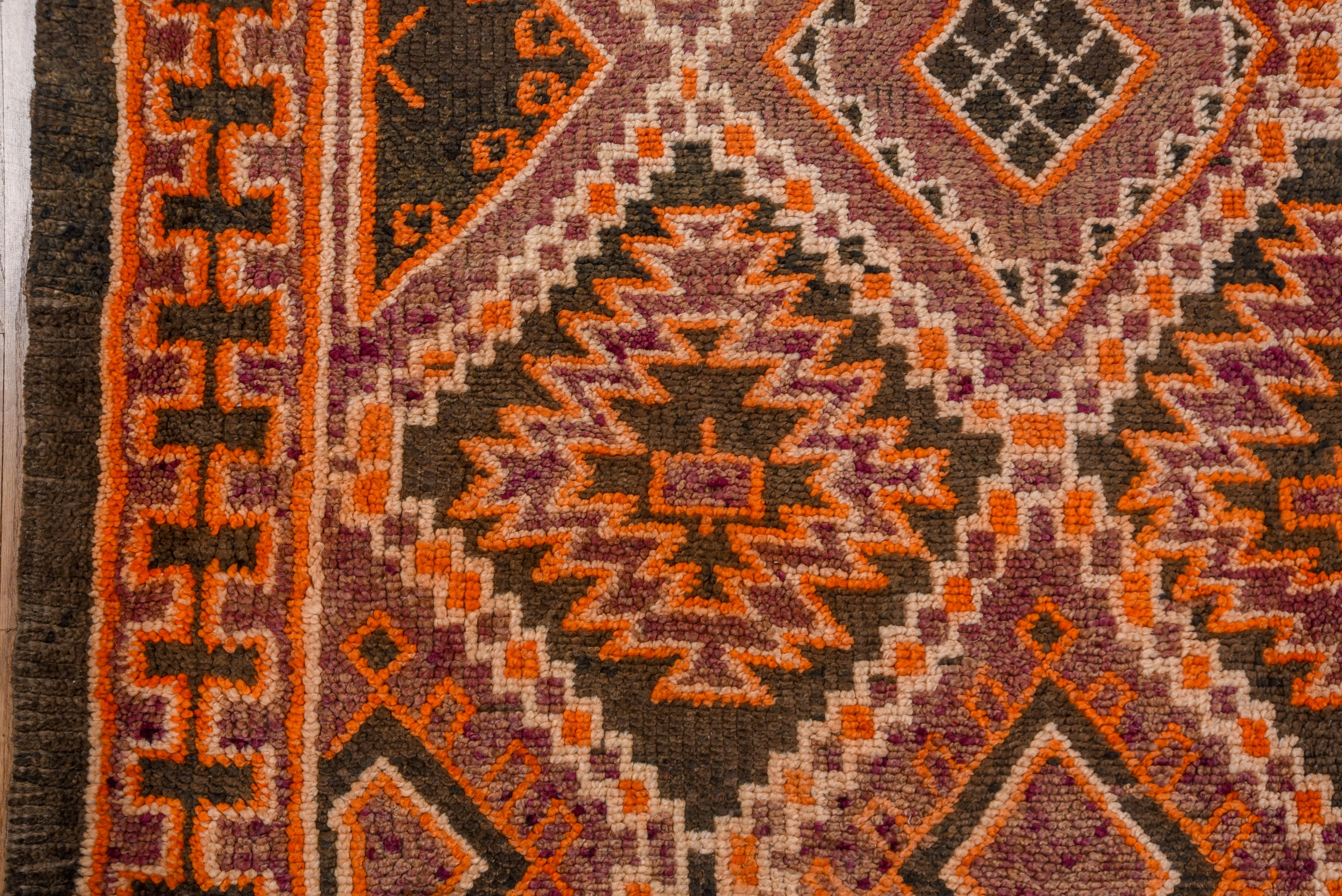This brightly colored tribal carpet shows an ivory diamond lattice with smaller diamonds, goidal ashiks, squares and stepped mini-medallions. Orange, mauve and red accents.Main border with a chain of rectangles accented in orange, ivory and red.