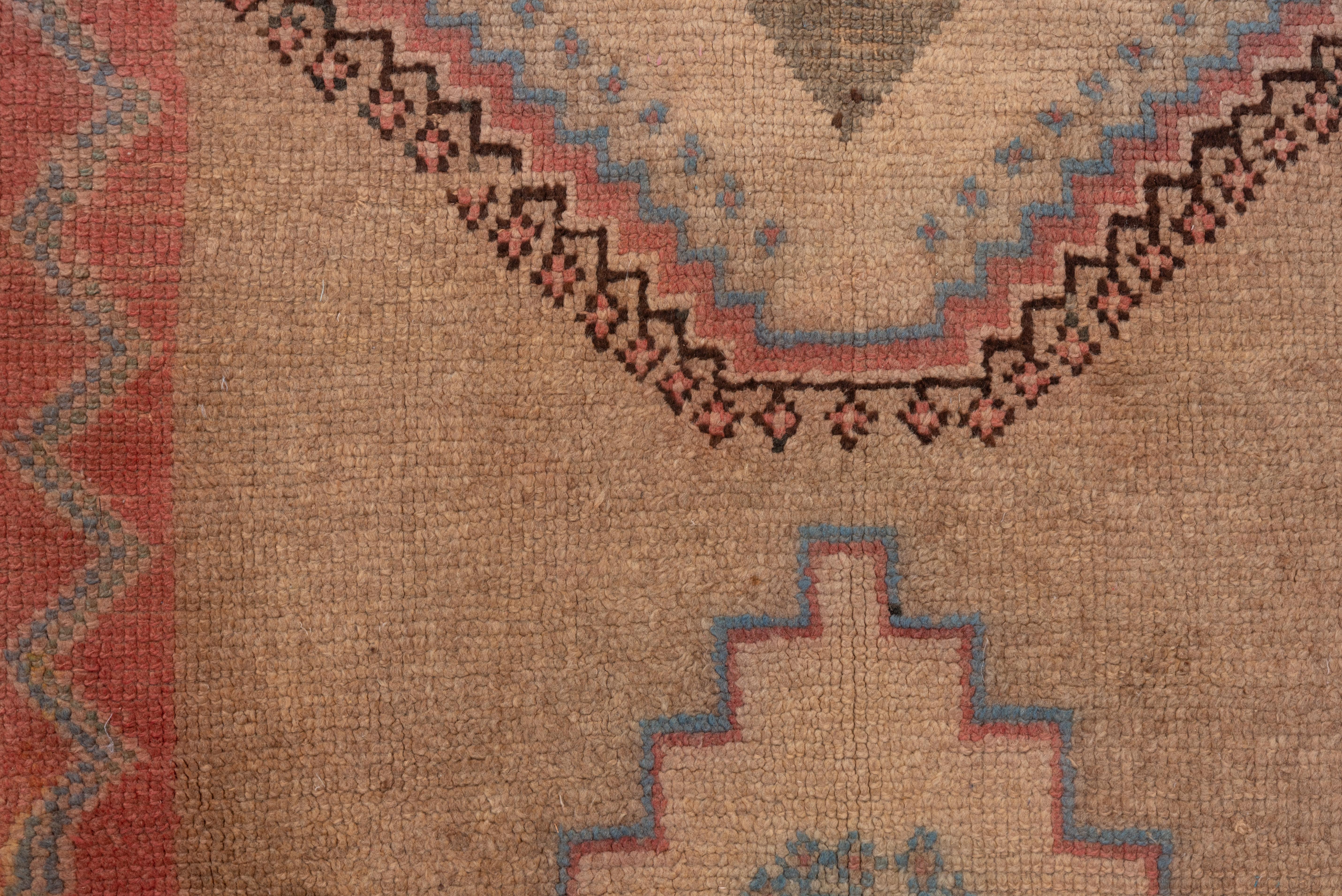 With faint echoes of Persian Sarabs, this vintage tribal Moroccan runner features a light camel-tan field with a multiply pinched ecru, dark brown and light blue medallion vertically flanked by large, ivory stepped diamonds. Pale red narrow border