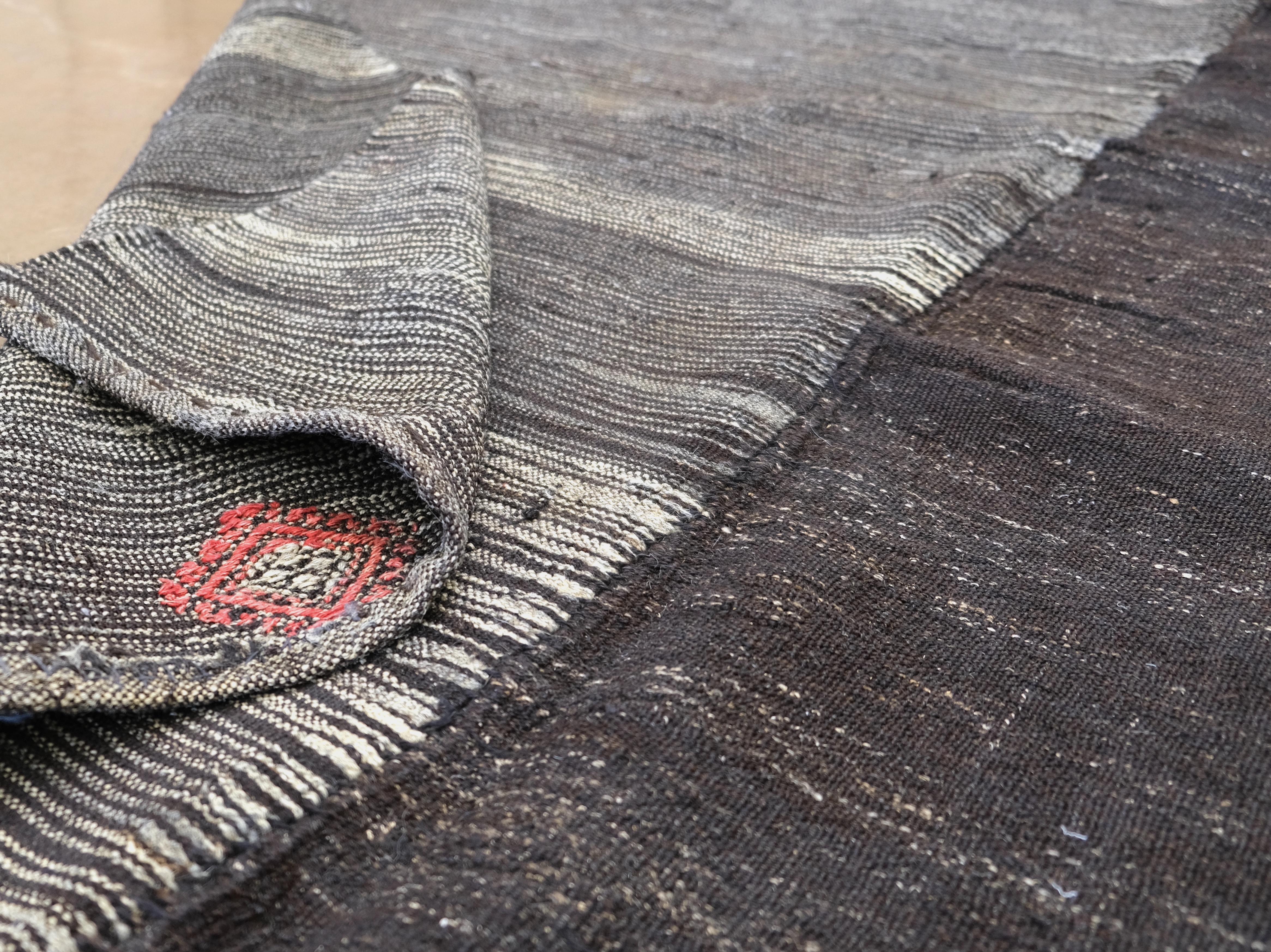 Discover the timeless beauty of this vintage hand-woven and goat hair rug from Turkey, featuring a unique dual-tone design that seamlessly combines solid and striped patterns. This one-of-a-kind rug incorporates subtle tribal motifs in vibrant pops