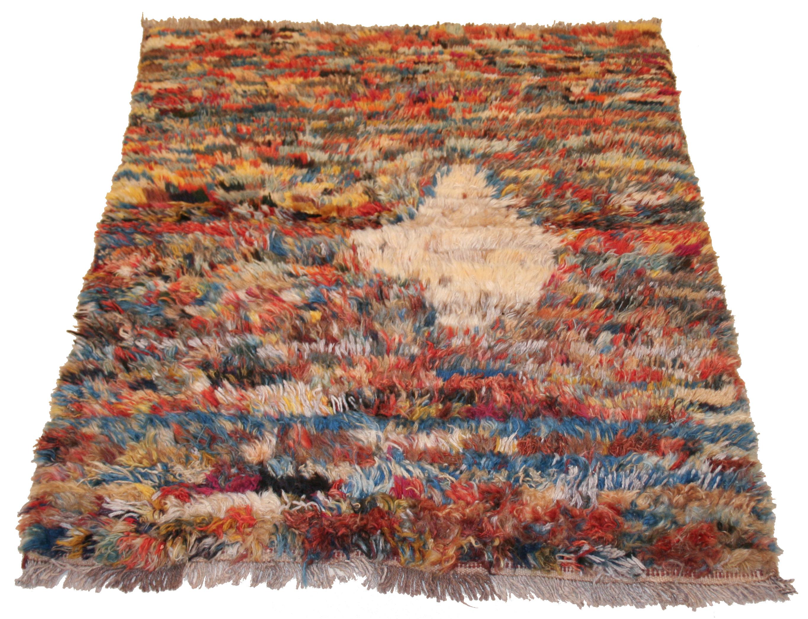 Characterized by a polychrome background obtained through the miscellany of coloured wools, this charming tribal rug is further distinguished by an abstract looking ivory diamond element placed off the central axis of the composition. A genuinely
