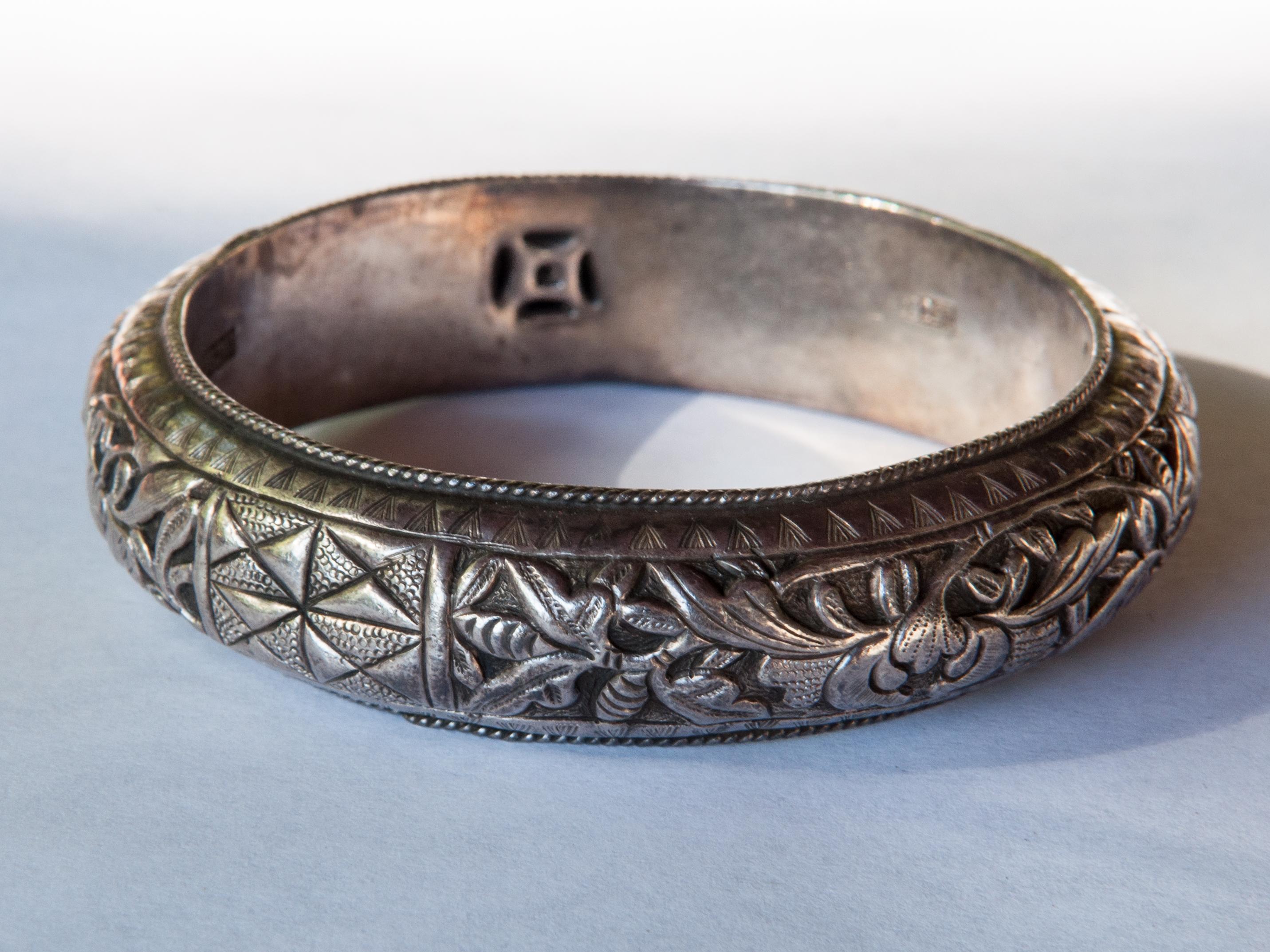 Vintage tribal silver bracelet with floral design from the Hmong of Southwest China, mid-20th century. This hand worked hollow silver bracelet comes from the Hmong ethnic minority of southwest China. It was most likely one of a pair, often presented