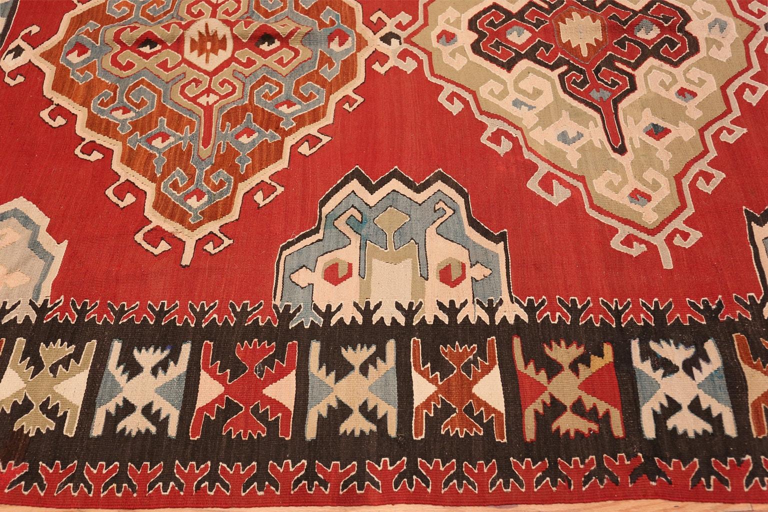 Red background tribal design vintage Turkish Kilim rug, country of origin: Turkey, circa second quarter of the 20th century - Size: 6 ft 9 in x 10 ft 3 in (2.06 m x 3.12 m). True to the striking tribal vintage rug style of Turkish Kilim rugs, this
