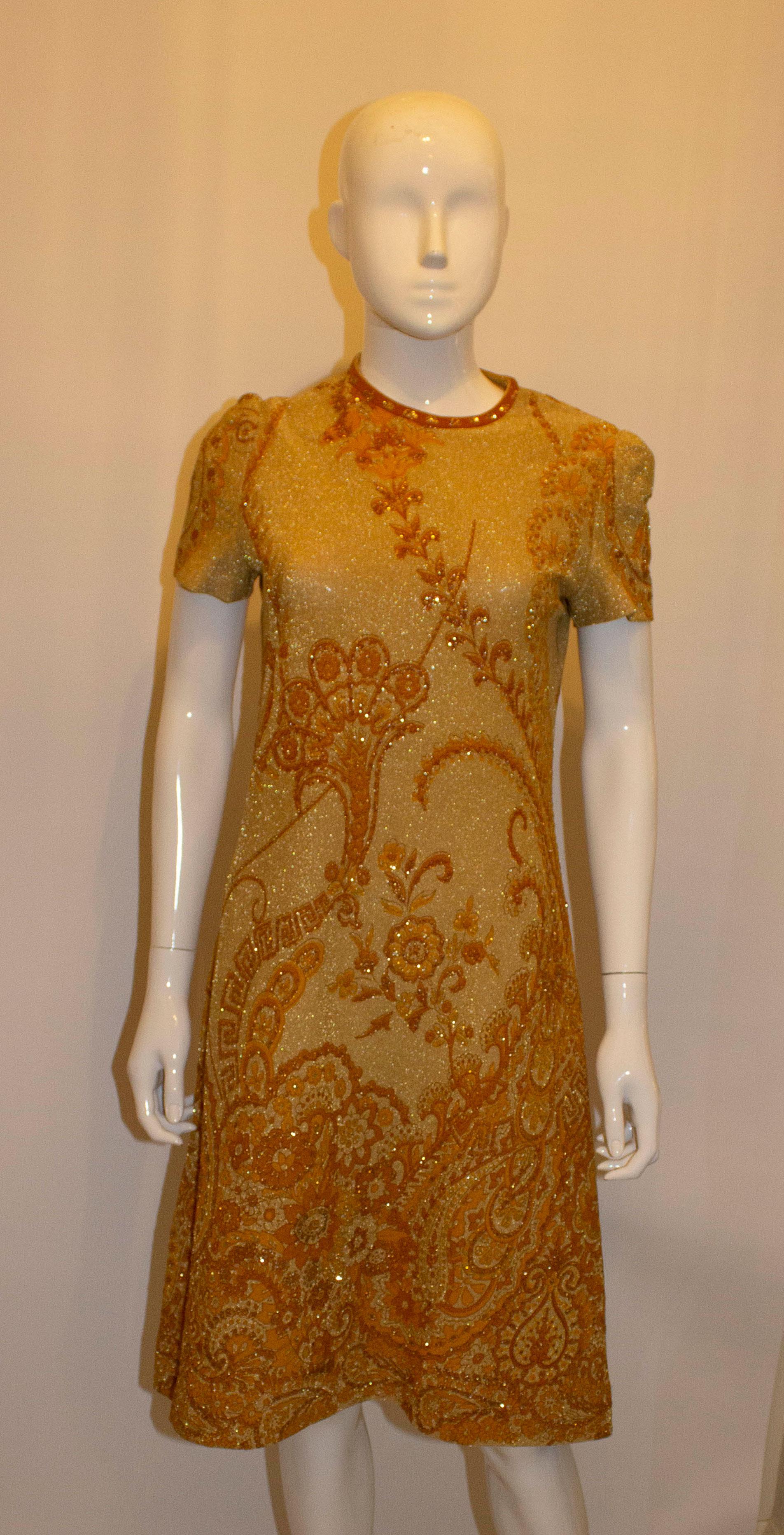 A chic vintage cocktail dress by Tricosa. The dress is in a soft gold colour with brunt orange print.  It has a round neckline, central back zip, and is unlined. 
Measurements: Bust 35'', length 41 '' plus hem 1 3/4''
