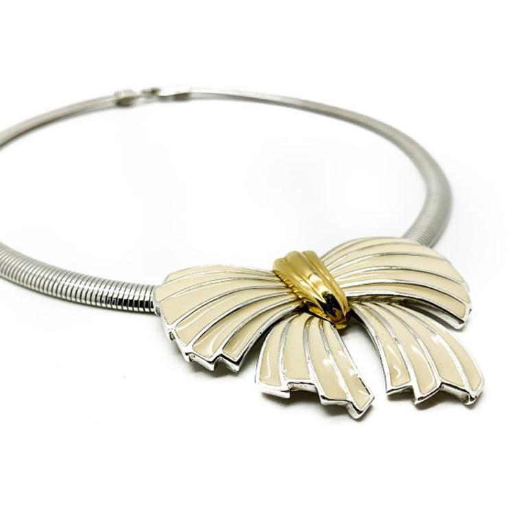 Vintage Trifari Bow Necklace. A fabulous statement collar style with a cool and feminine vibe from the legendary House of Trifari. Featuring a silver tone, flexi snake link collar with a large bow motif in cream enamel and gold plate detailing. In