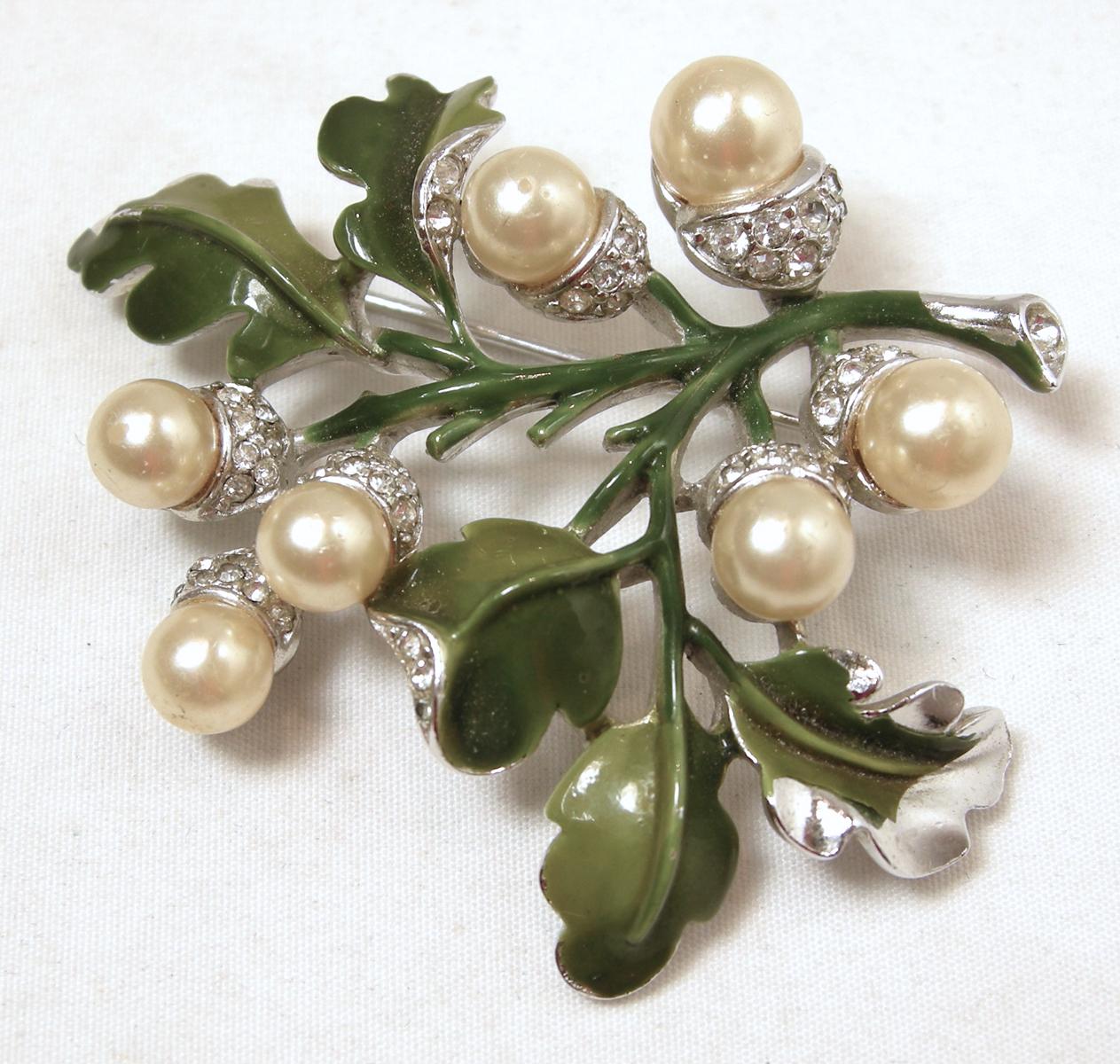 This vintage Trifari brooch has a floral design with faux pearls, clear crystals and green enamel leaves on a rhodium silver tone setting.  In excellent condition, this brooch measures 2-1/4” x 2”.