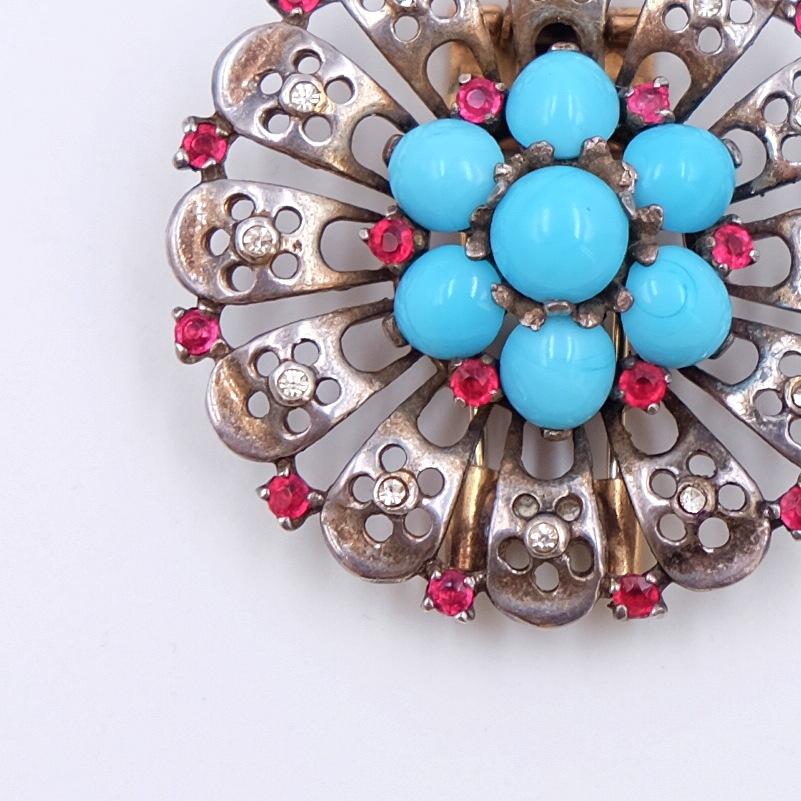 Stunning Trifari dress clip in great condition made of sterling silver and decorated with red and white rhinestones and turquoise cabochons. Looks fantastic with any outfit, especially with wool sweaters and coats.

Period: 1940s
Hallmark: Trifari