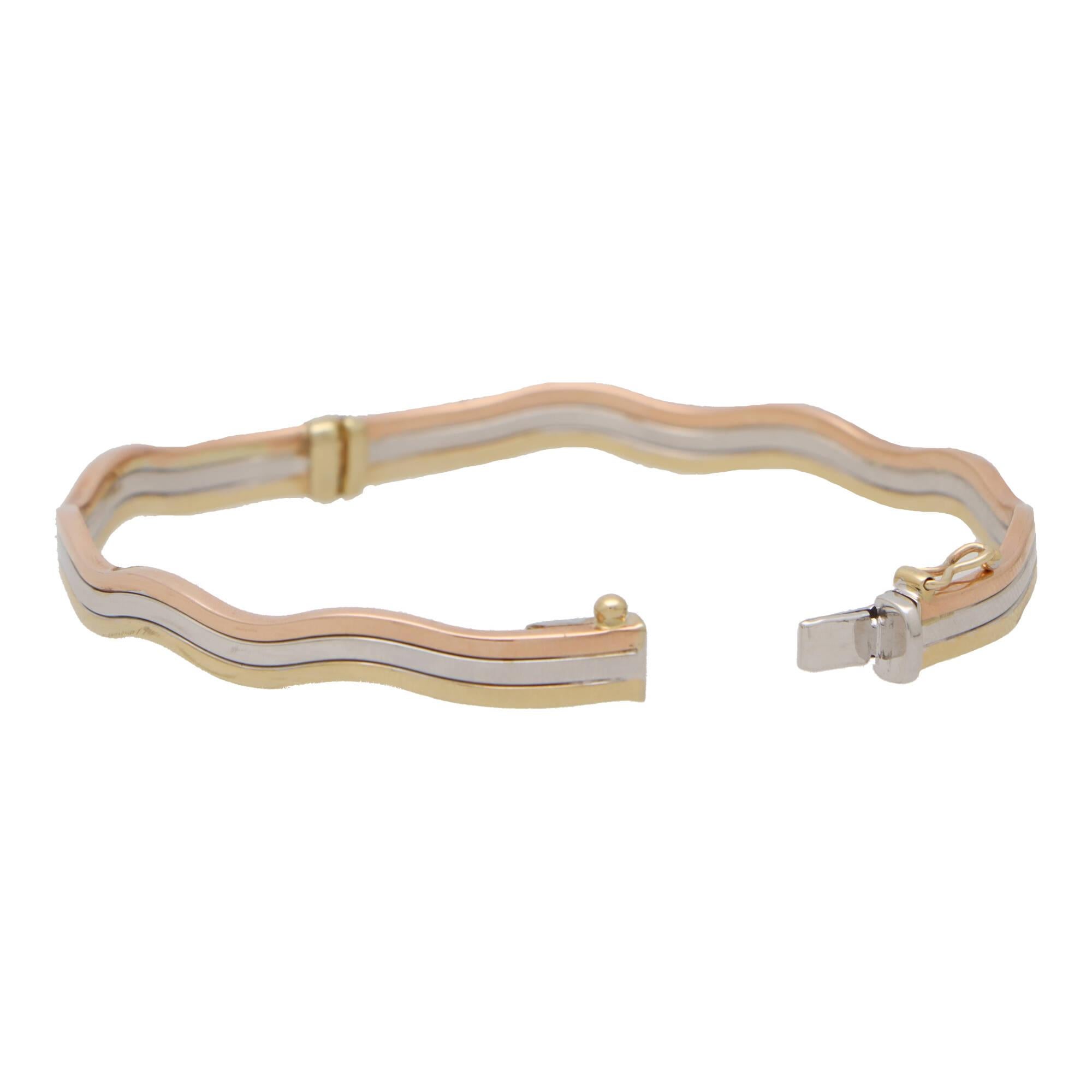  A beautiful hinged trinity wave bangle set in 9k yellow, rose and white gold.

The bangle is composed of three soldered tri-colored bangles which are all interlocked together in a unique wave trinity design. If you love the trinity design but