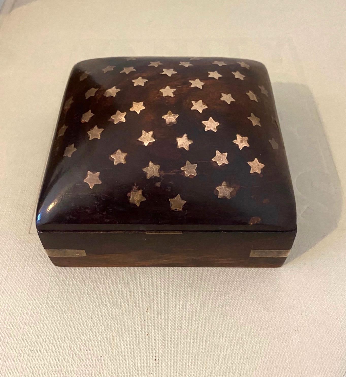 Mid-Century Modern handmade trinket box in rosewood. The box has a square form with a dome top. The lid features beautiful brass star inlays and the corners have brass metal accents. The brass exhibits some patina which only adds to the allure and