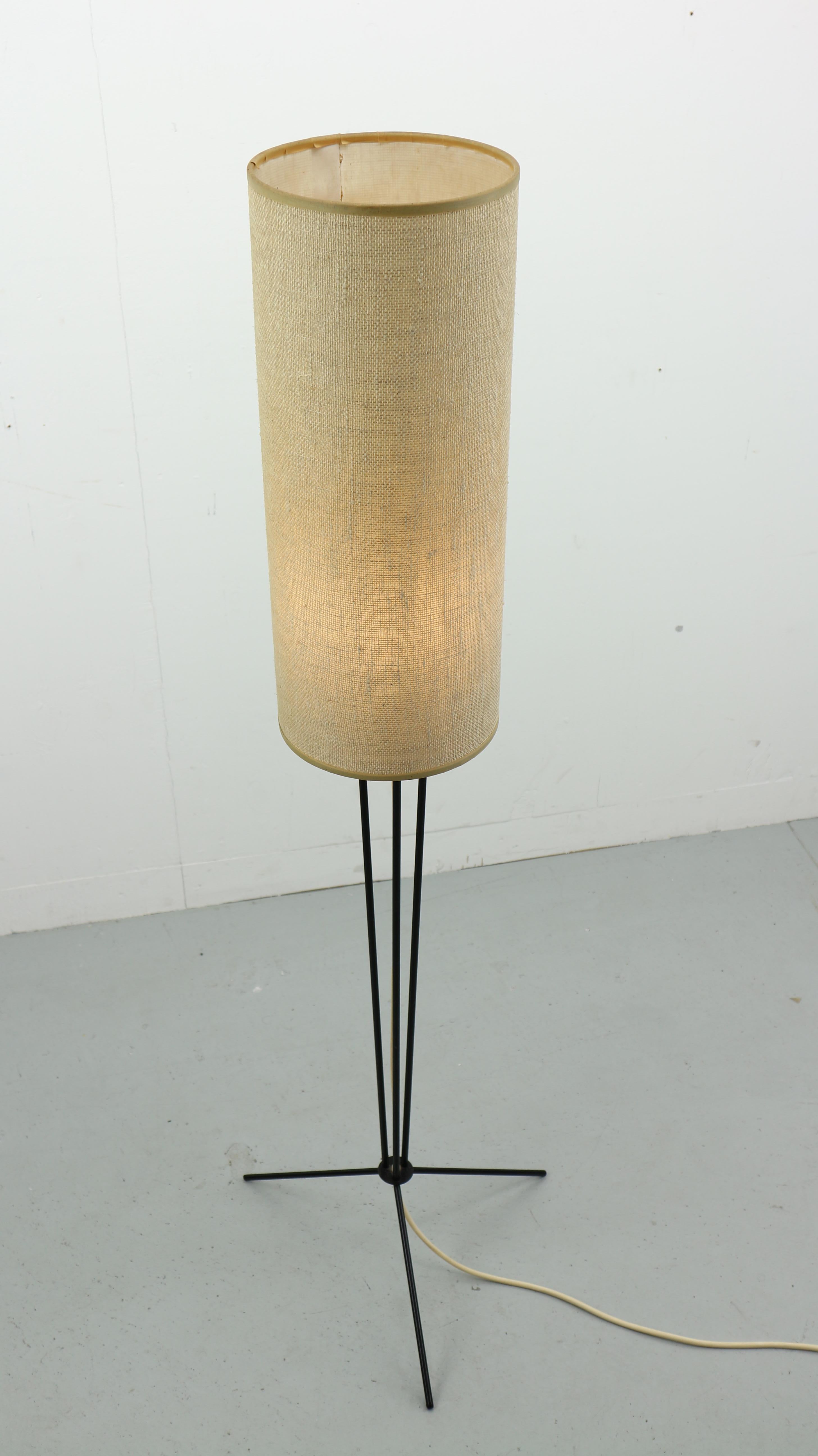 Vintage tripod floor lamp is made in 1950s.
The lamp stands on a three black metal feet and comes with an original sand color lampshade.
This minimalistic lamp is a beautiful interior accent to your design home.
 