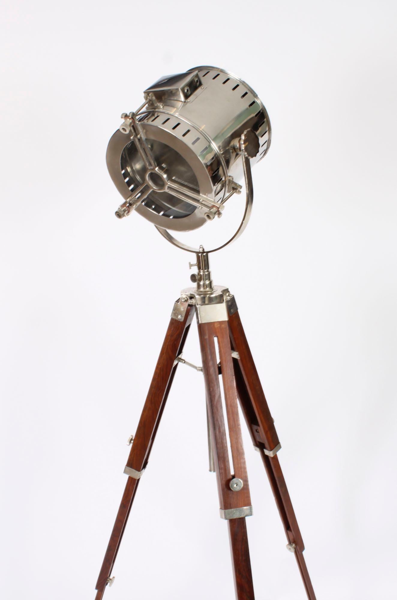 This is a highly attractive interwar revival industrial design tripod searchlight floor lamp, late 20th Century in date.

This splendid nautical-inspired floor standing lamp is crafted with a swiveling polished nickel searchlight mounted on an