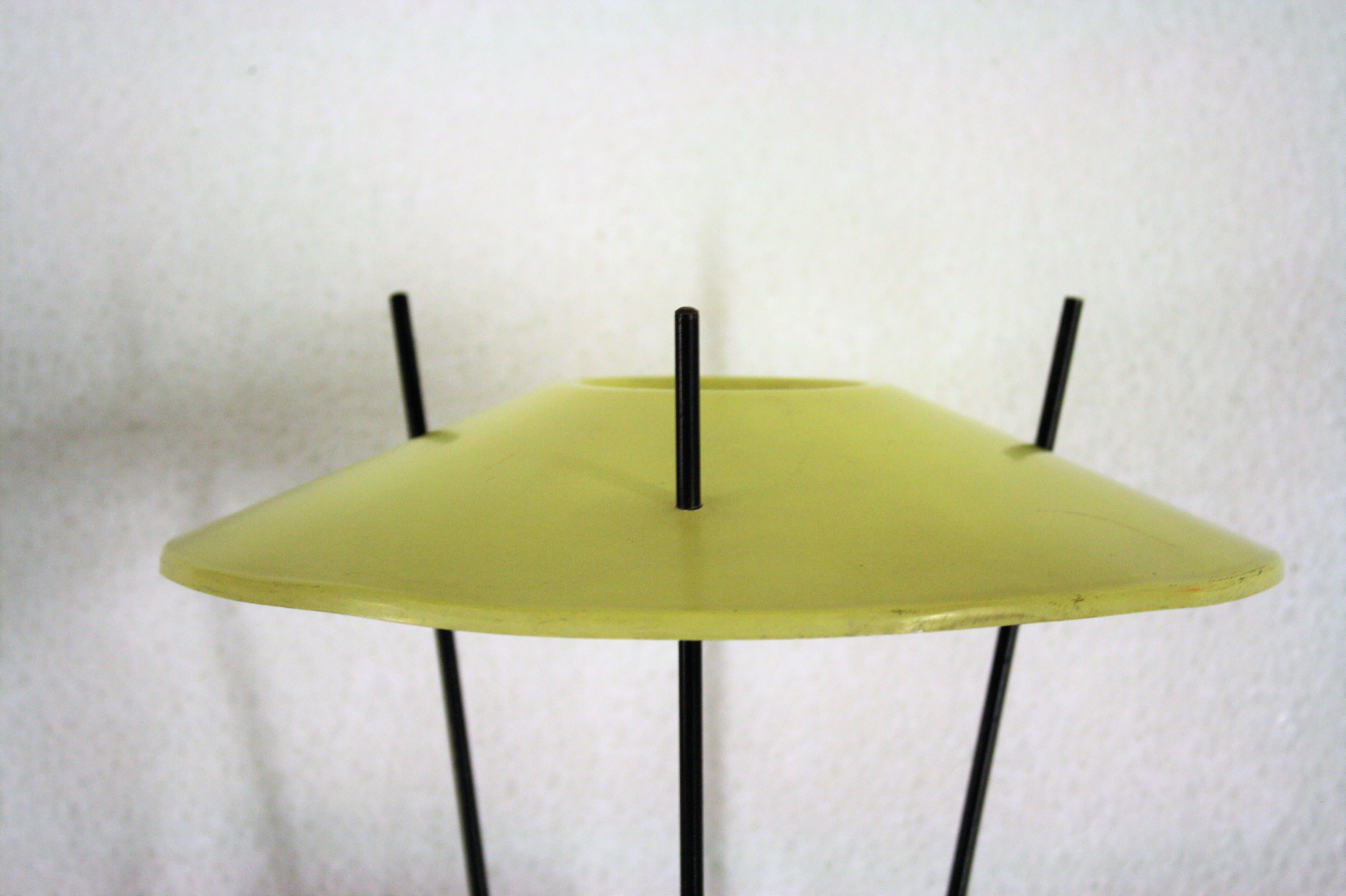 Rare atomic design midcentury table lamp.

The lamp features a yellow enameled shade mounted on a smart designed black metal base and the original blown glass hurricane shade.

Although no specific designer has been found, this lamp is a rare