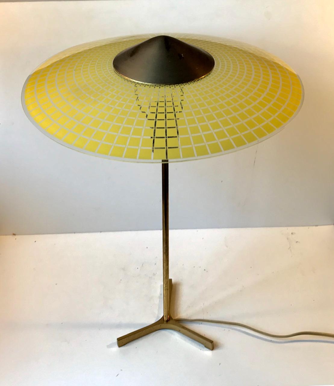 A lean and 'delicate' table or desk light composed of a Tristan brass base and checkered yellow glass shade set in a hooded brass top. It was designed anonymously in Switzerland during the late 1950s-early 1960s in a style reminiscent of Stilnovo.