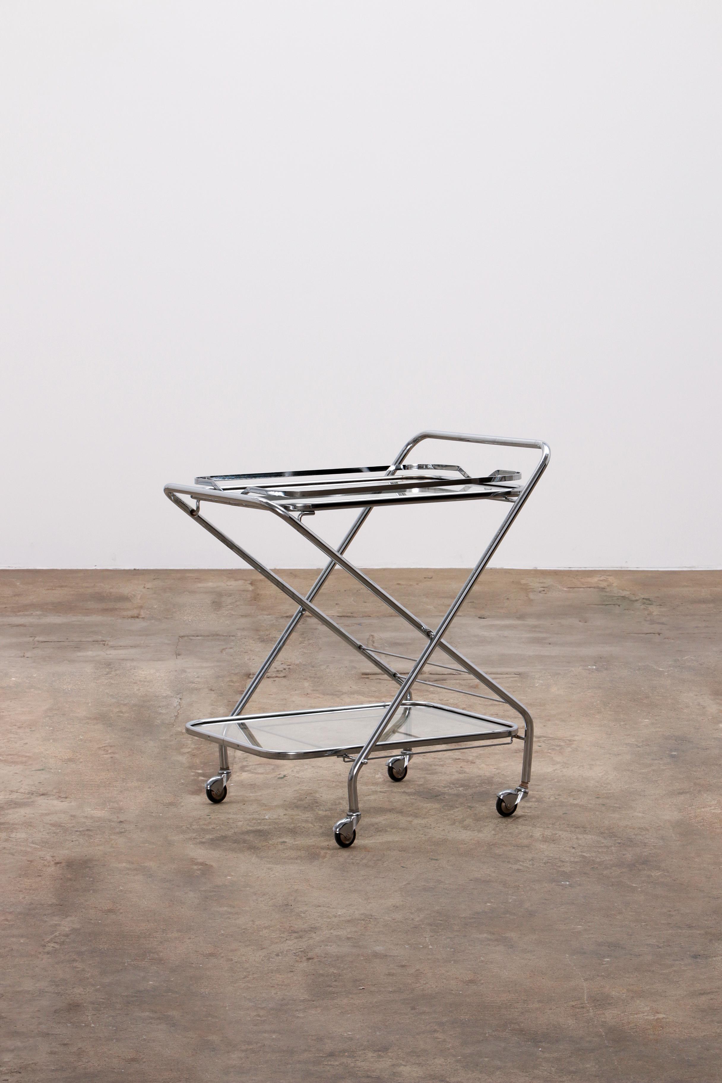 A beautiful trolley with castors and two beautiful glass plates.Typical design of the 1960s, combines perfectly in both a modern and vintage interior

The trolley is collapsible and therefore easy to put away. It is chrome-plated and the glass