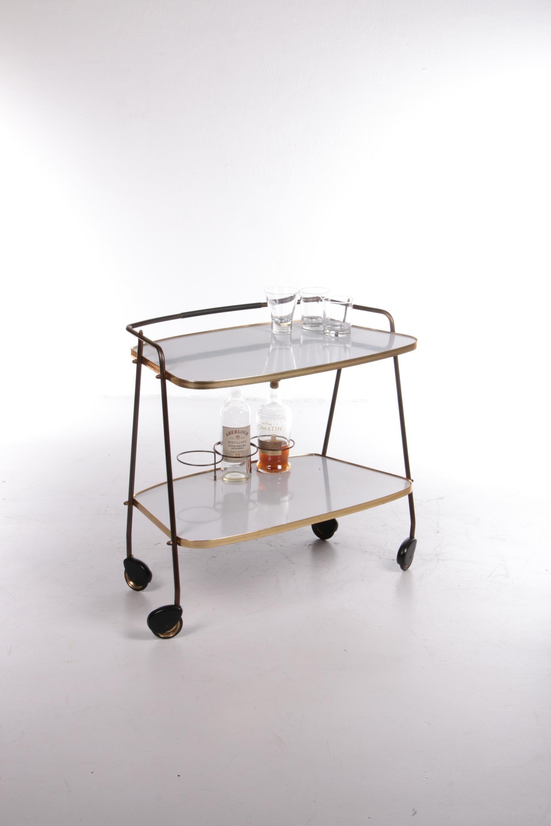 Vintage Trolley tea cart or beautiful bar cart, 1960s

This is a beautiful trolley from the 1960s.

The lower leaf is white and the upper leaf is also white. The frame is made of beautiful gold brass. The lower floor also has a nice rack to put