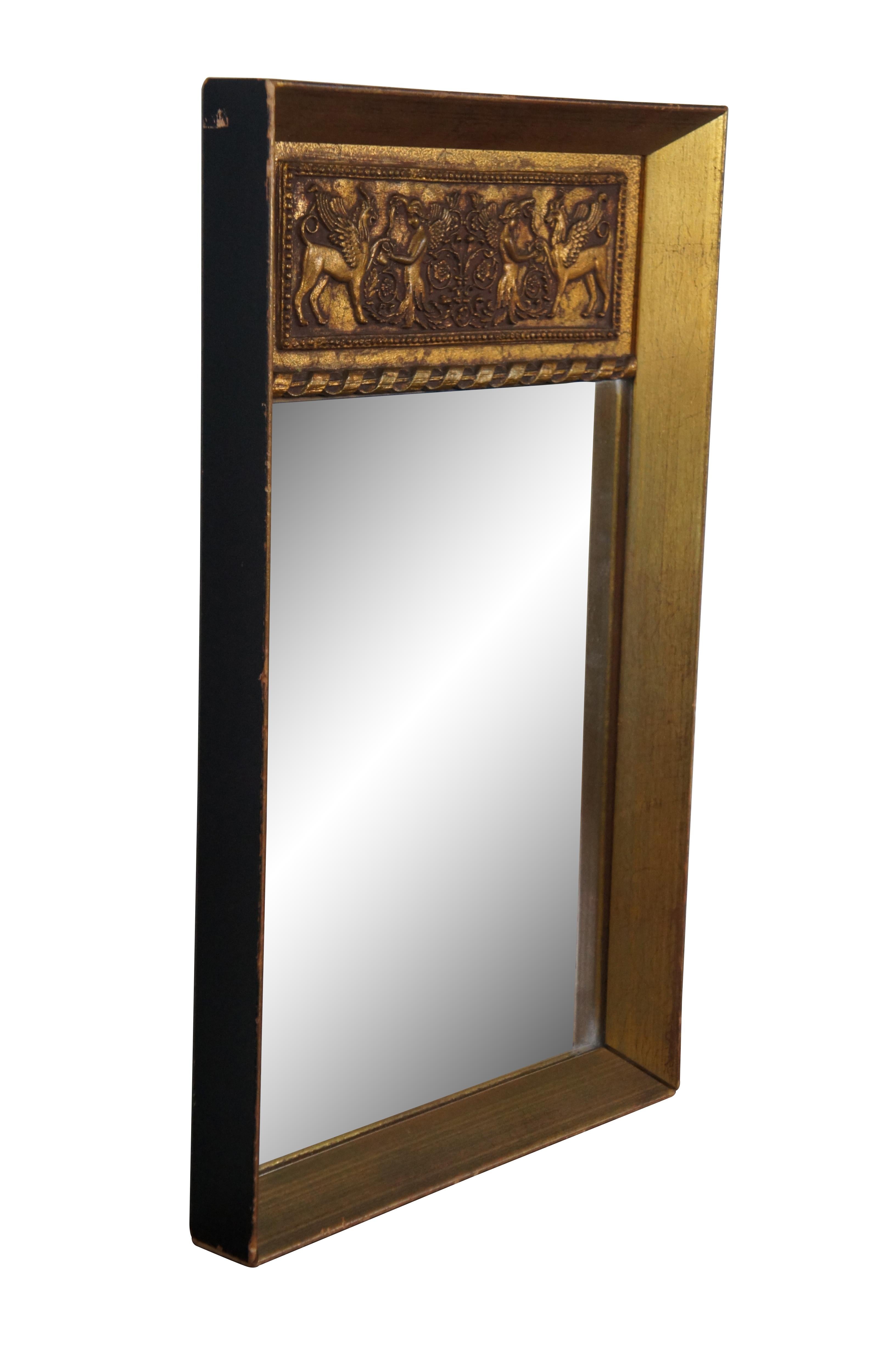 Vintage gilt wood trumeau style wall mirror featuring a rectangular beveled frame topped with a spiraling ribbon dividing the mirror from a neoclassical relief showing a winged angel figure pouring wine or water into a jug for a chimera-like