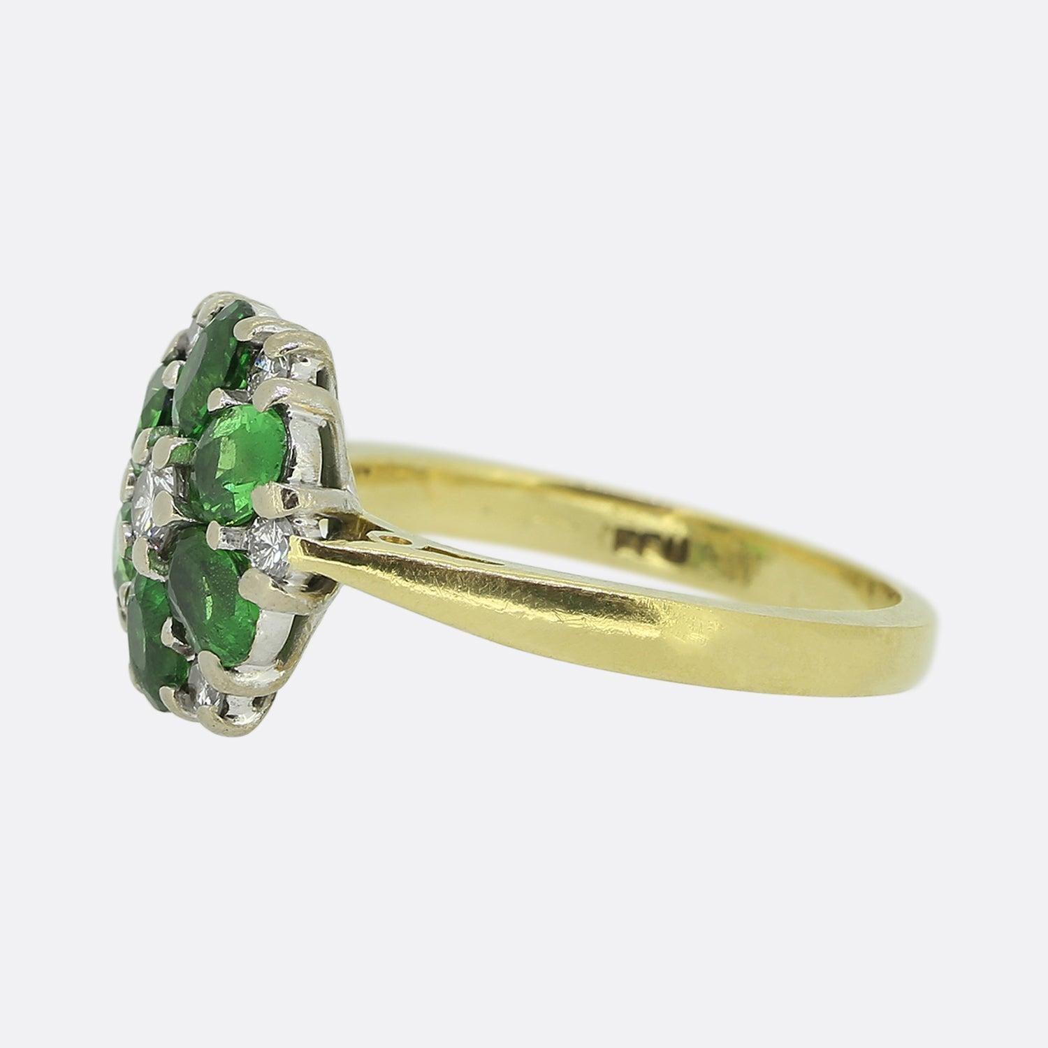 Here we have a delightful garnet and diamond cluster ring. This vintage piece showcases a collection of oval shaped tsavorite garnets in a round formation. These gemstones are perfectly matched and possess an alluring electric green colour tone.