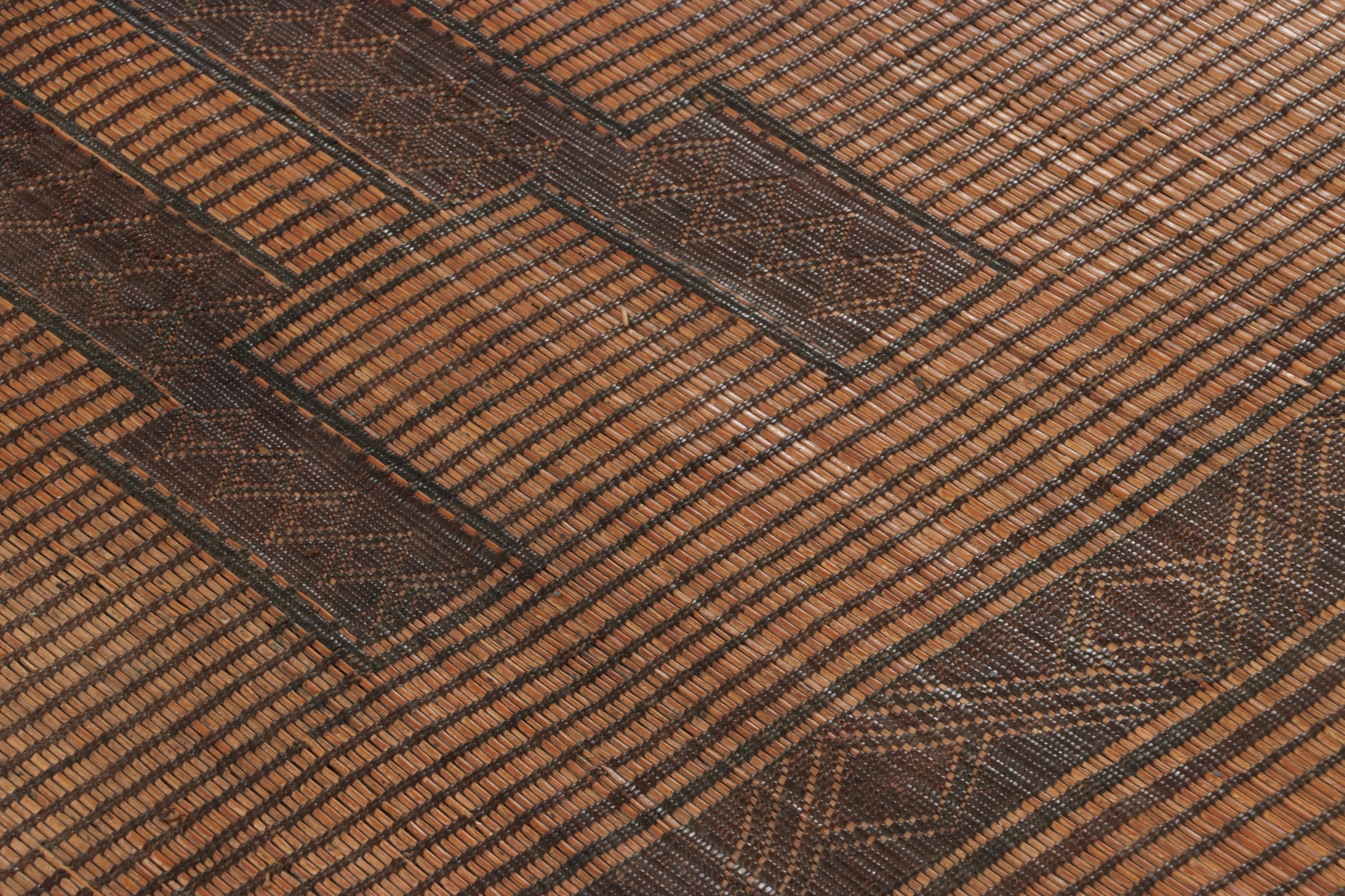 Ce tapis et revêtement de sol vintage est un tapis touareg 9x14 de la tribu nomade du même nom. Tissé à la main avec des roseaux et du cuir de chameau en Mauritanie vers 1950-1960, ses matériaux naturels apprécient les tons beige-brun, noir et crème