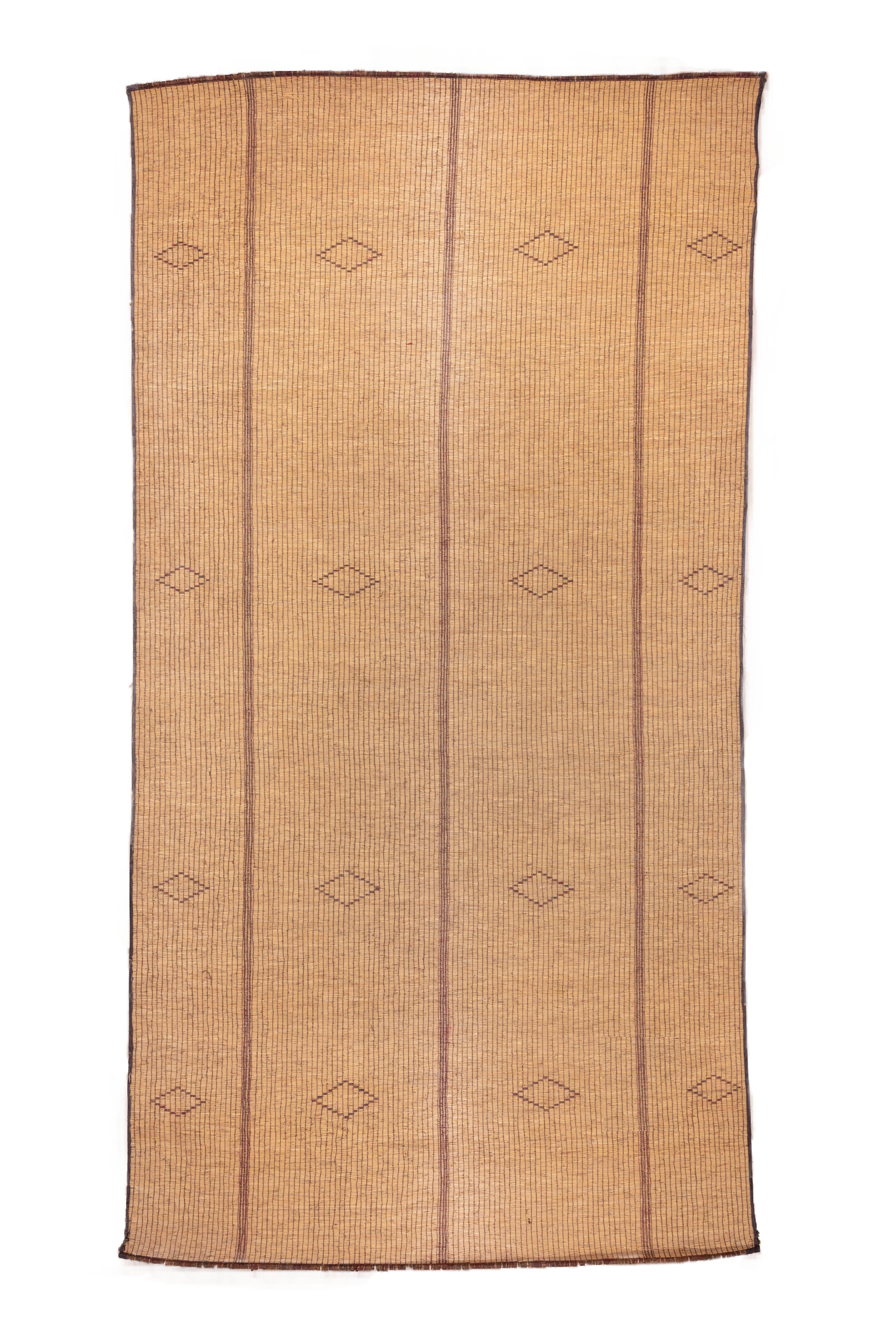 The oatmeal beige field is vertically divided into four wider and slightly narrower panels, uniformly decorated with subtle, floating small open lozenges. Sienna brown is manifested in the encompassing thin border. Good condition.

Tuareg Reed
