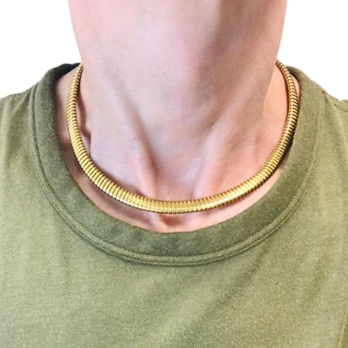 A vintage 18k gold tubogas necklace with a sleek, refined profile. Its subtle ridged surface reflect the light in a soft, understated way. 
The tubogas style is recognized for its smooth, coiled construction, created from interlocking bands of gold