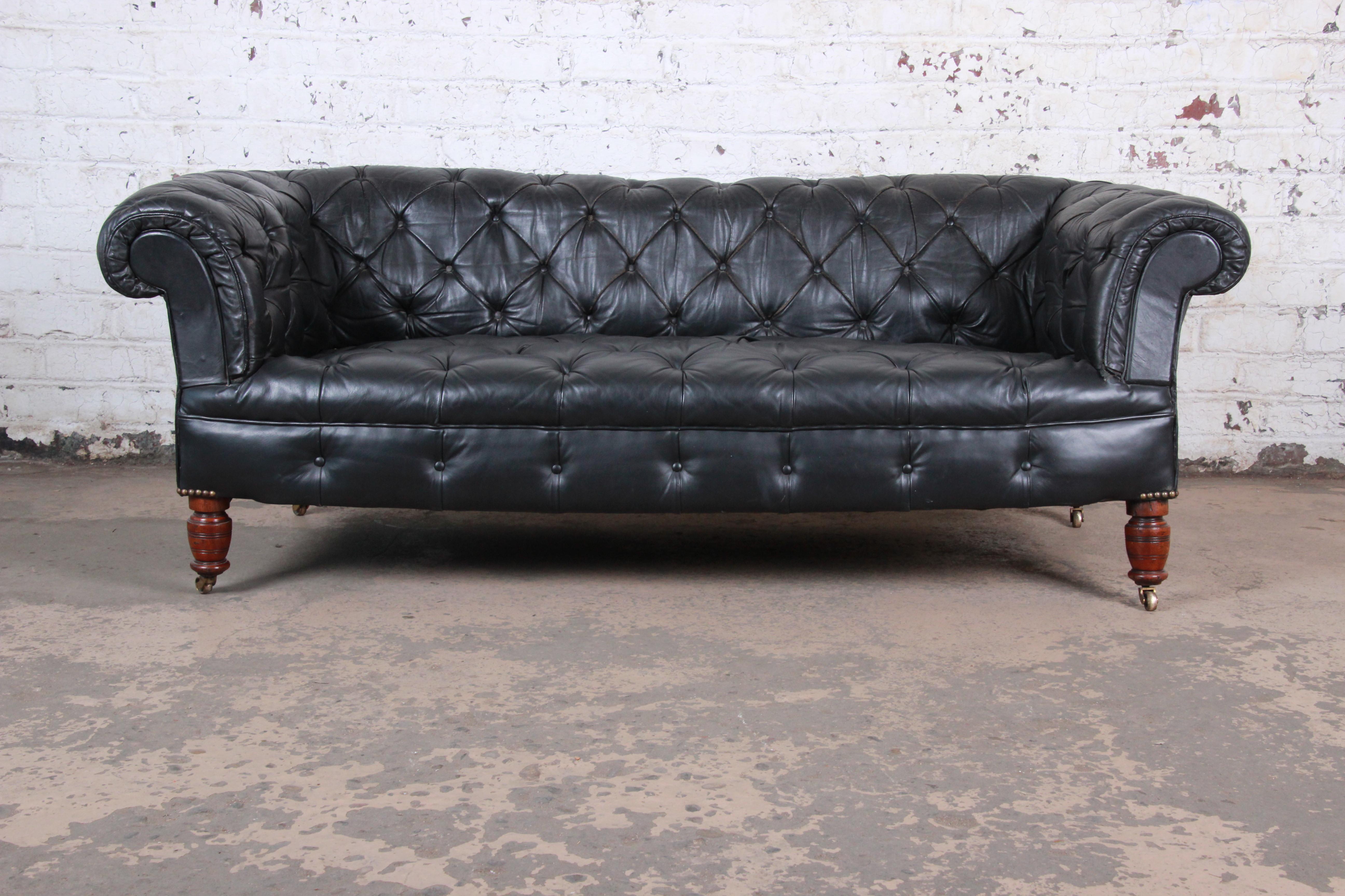A vintage tufted black leather Chesterfield sofa,

circa 1960s

Leather + turned walnut legs + brass casters

Measures: 76.5