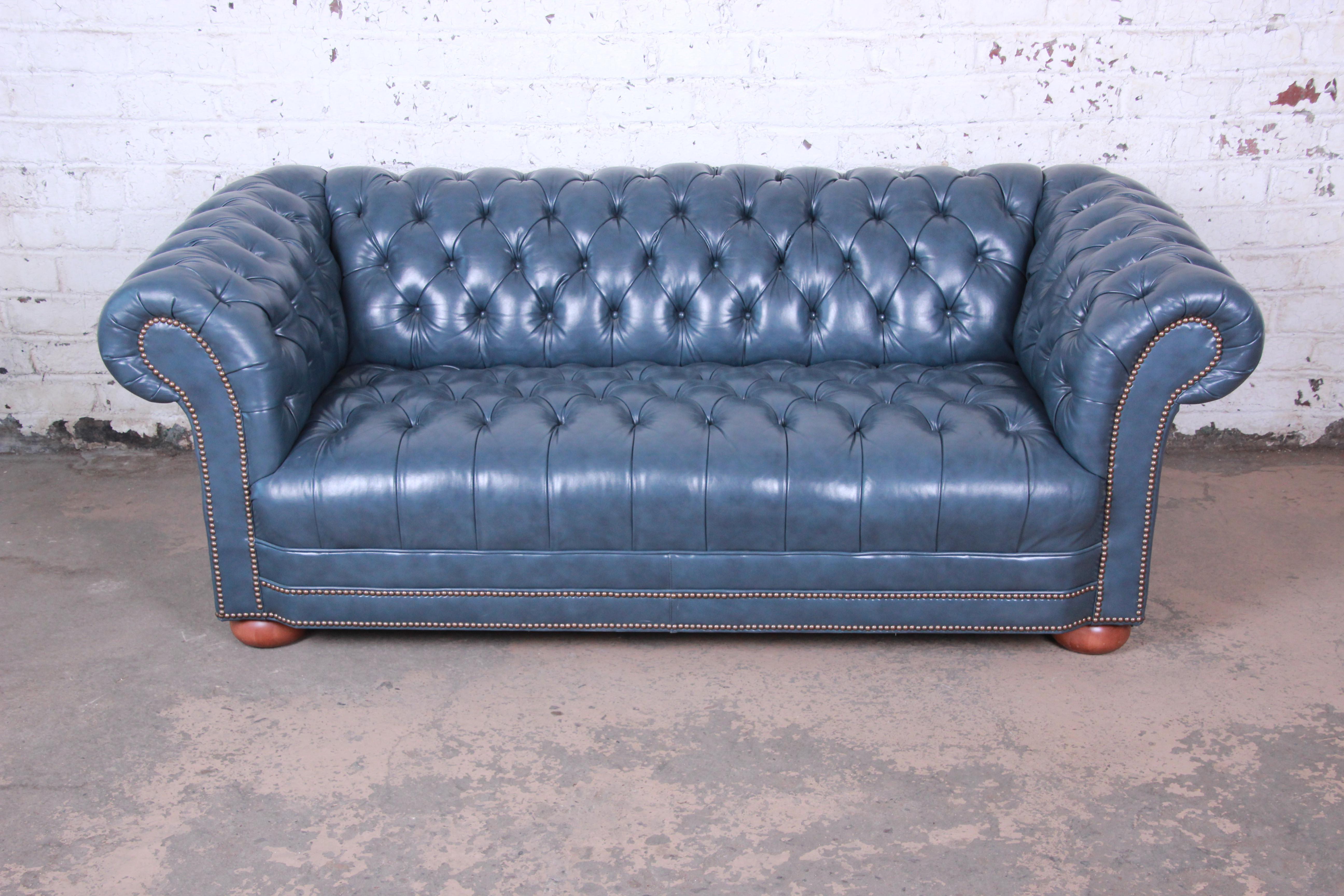 A stunning vintage tufted blue leather Chesterfield sofa. The sofa features gorgeous high grade tufted blue leather with brass nailhead trim. It sits on solid cherrywood bun feet. The sofa is very comfortable and in excellent condition.

The sofa