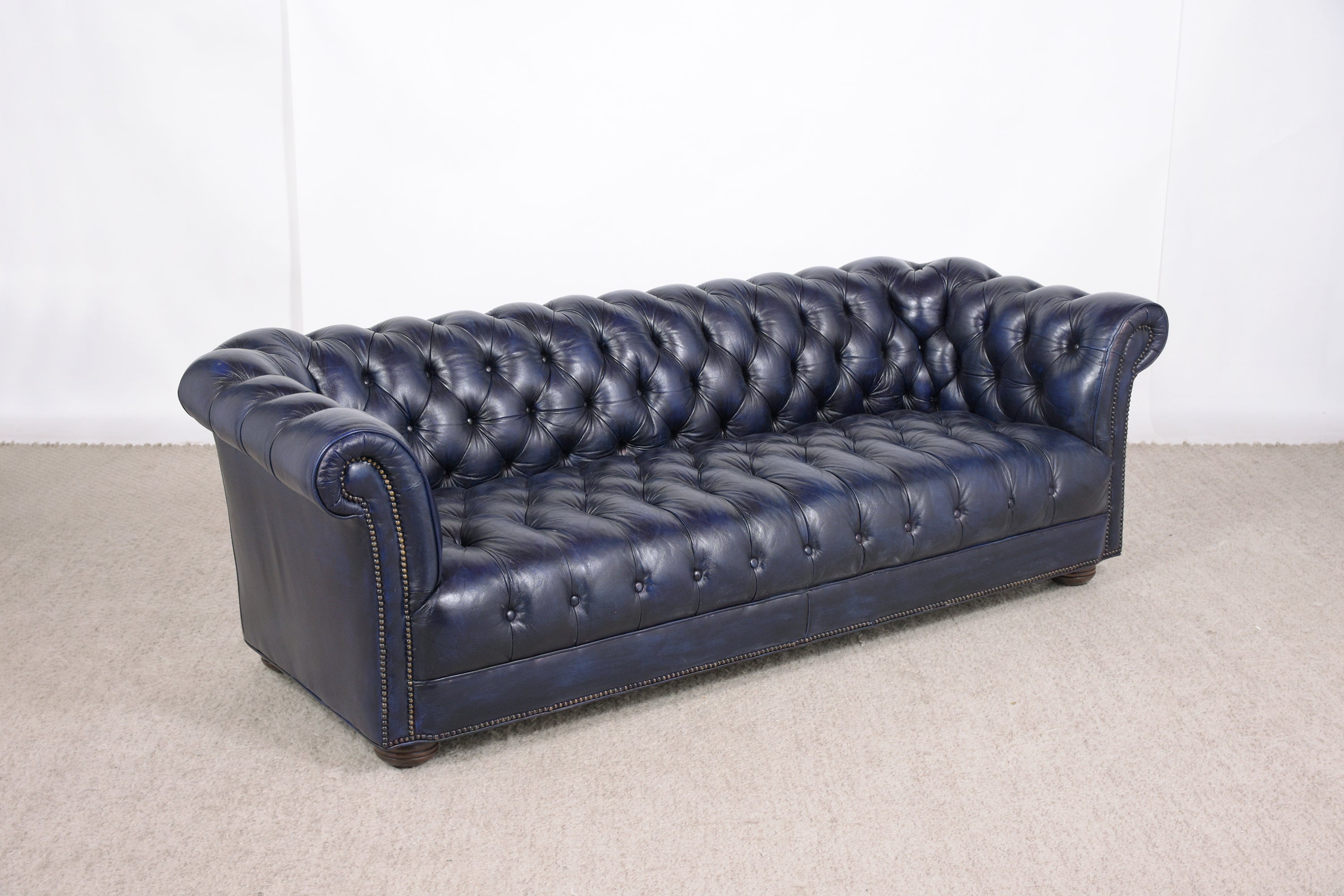 An extraordinary vintage blue leather tufted chesterfield sofa in great condition is crafted out of solid wood and leather combination completed restored by our professional craftsmen team and has been newly dyed in a navy blue color. The sofa has